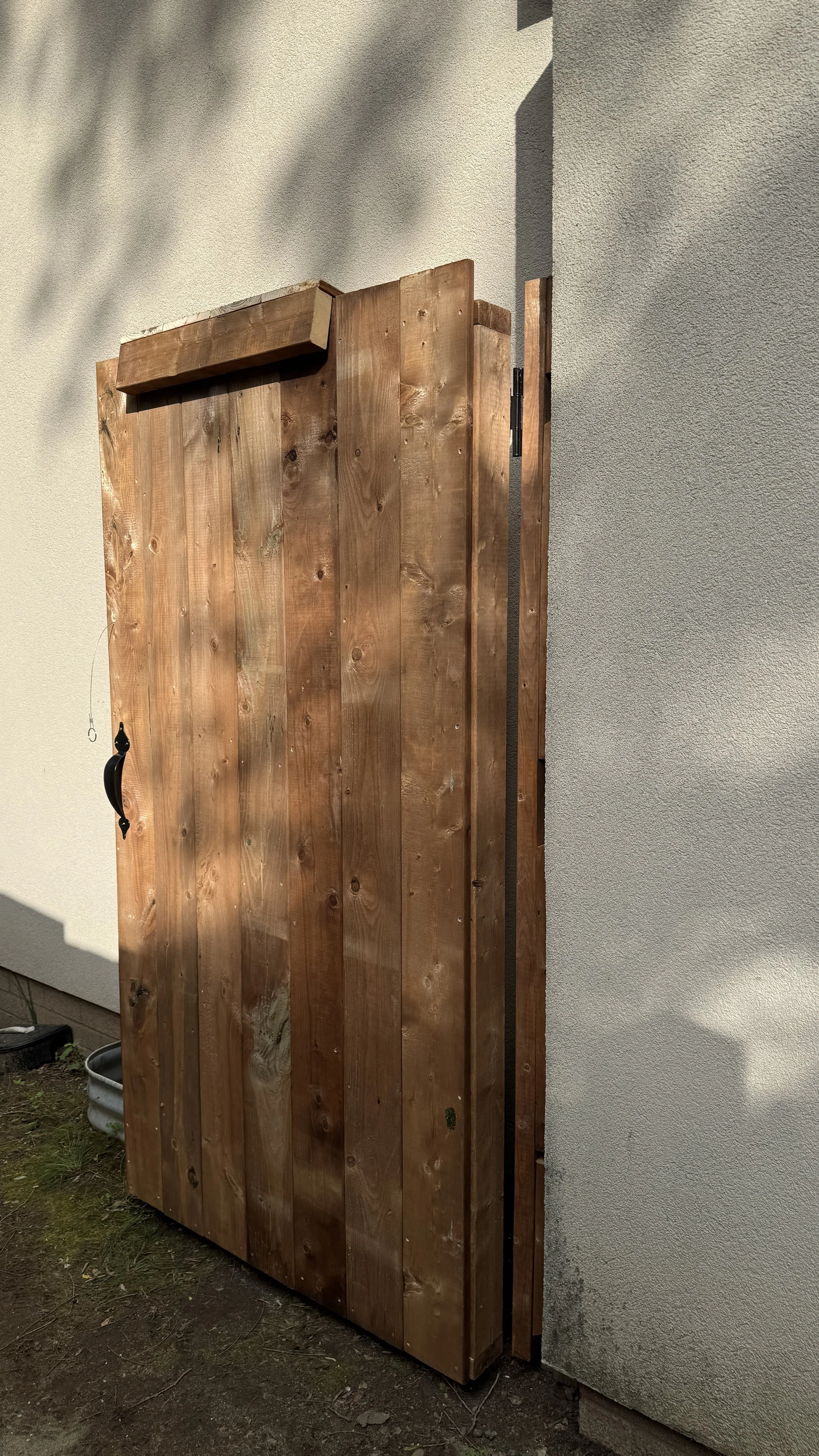 A wooden door with a black handle installed on a beige exterior wall of a building.