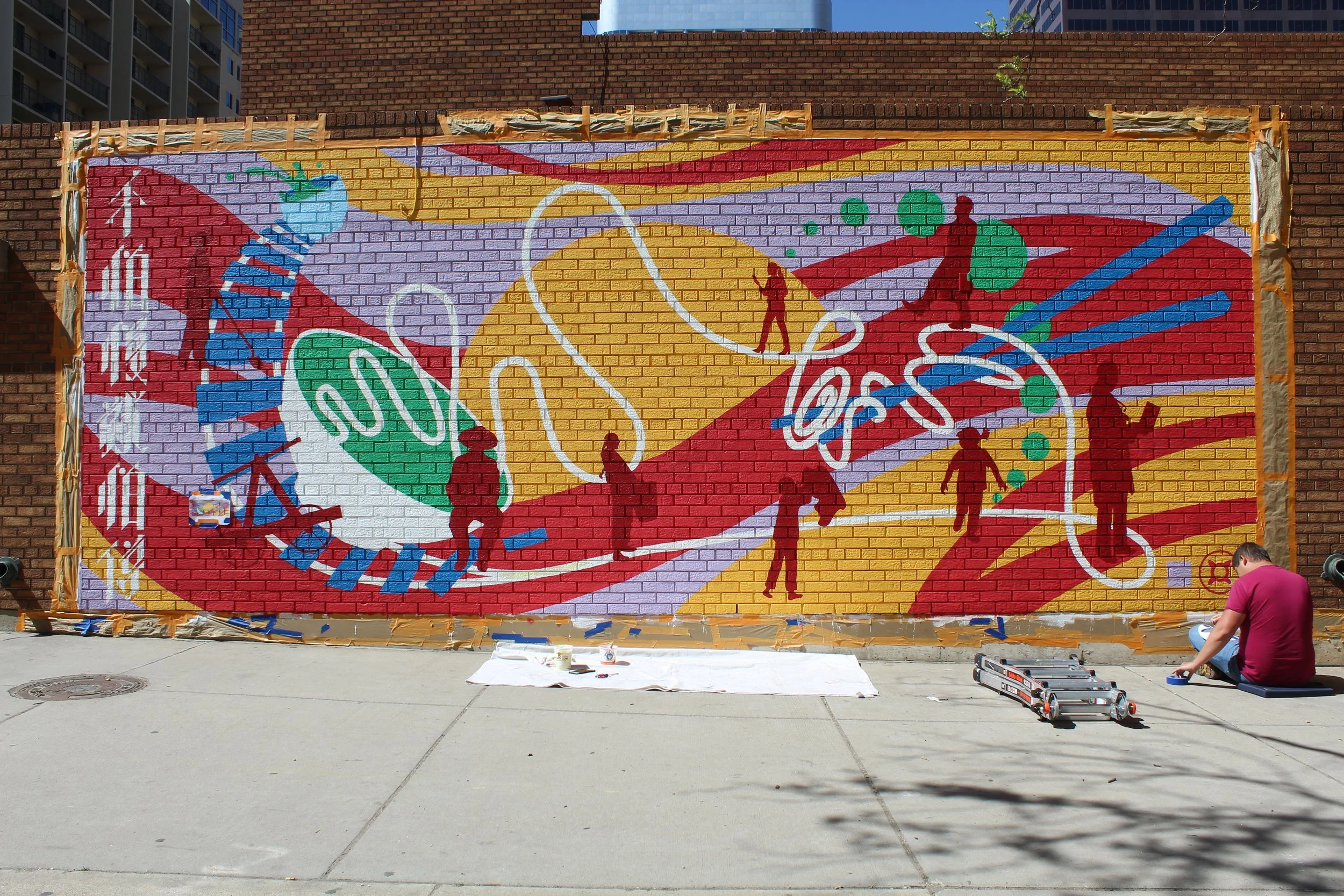 Nalye Lor's Chinatown mural nearly finished full of vibrant colors, a team member sits on the bottom right