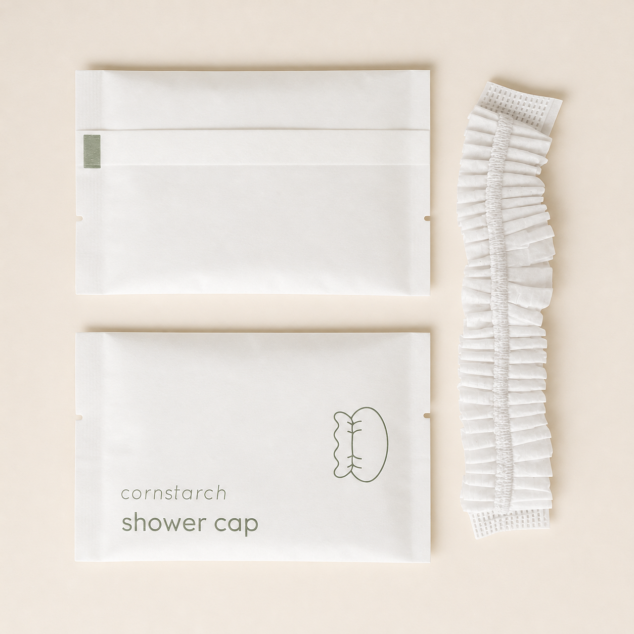 Cornstarch shower cap packaging with a white disposable shower cap displayed beside it