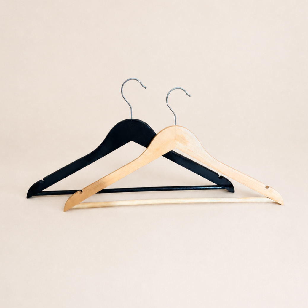 Two wooden clothes hangers, one natural wood and one black, against a light background