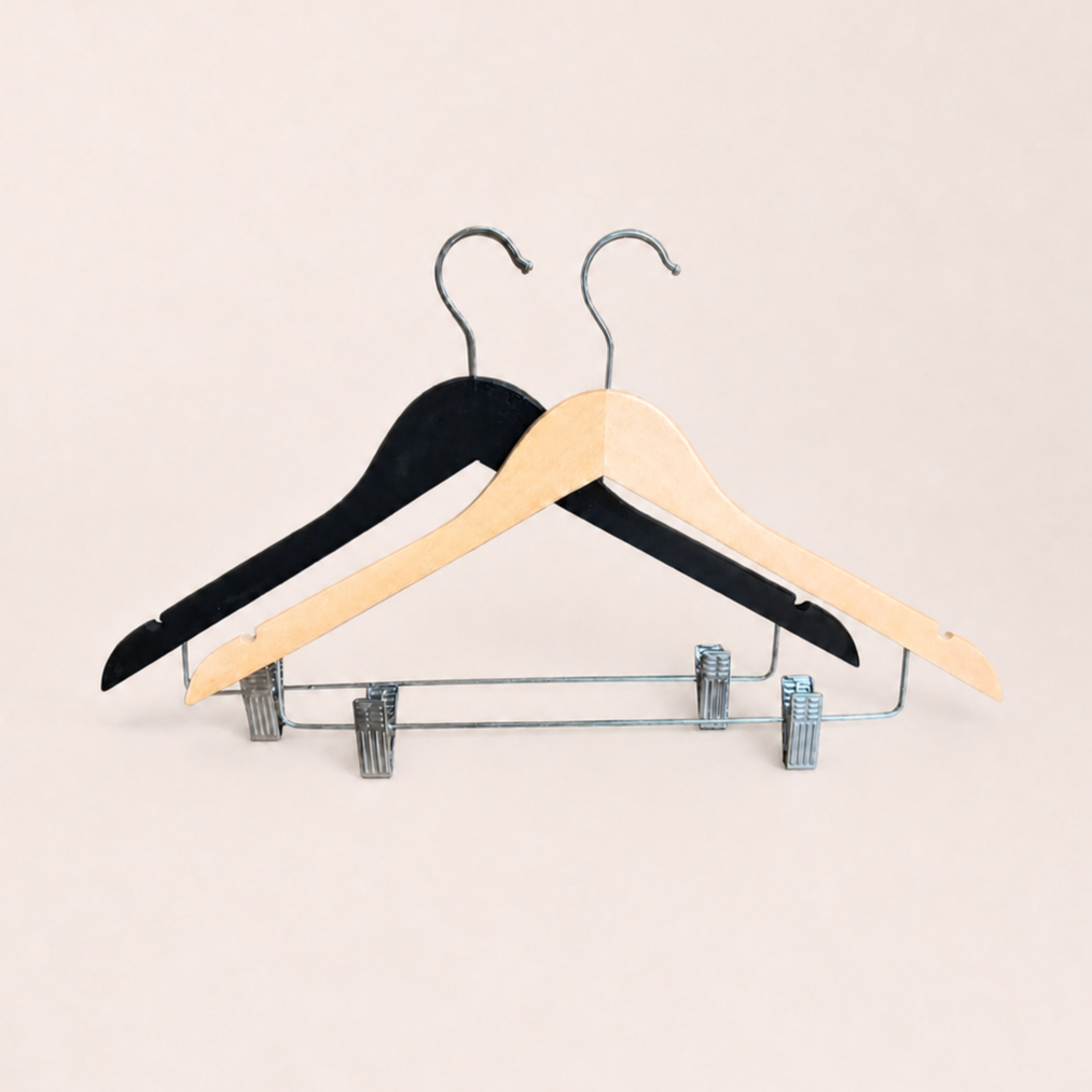 Two wooden clothes hangers with metal clips against a pale pink background