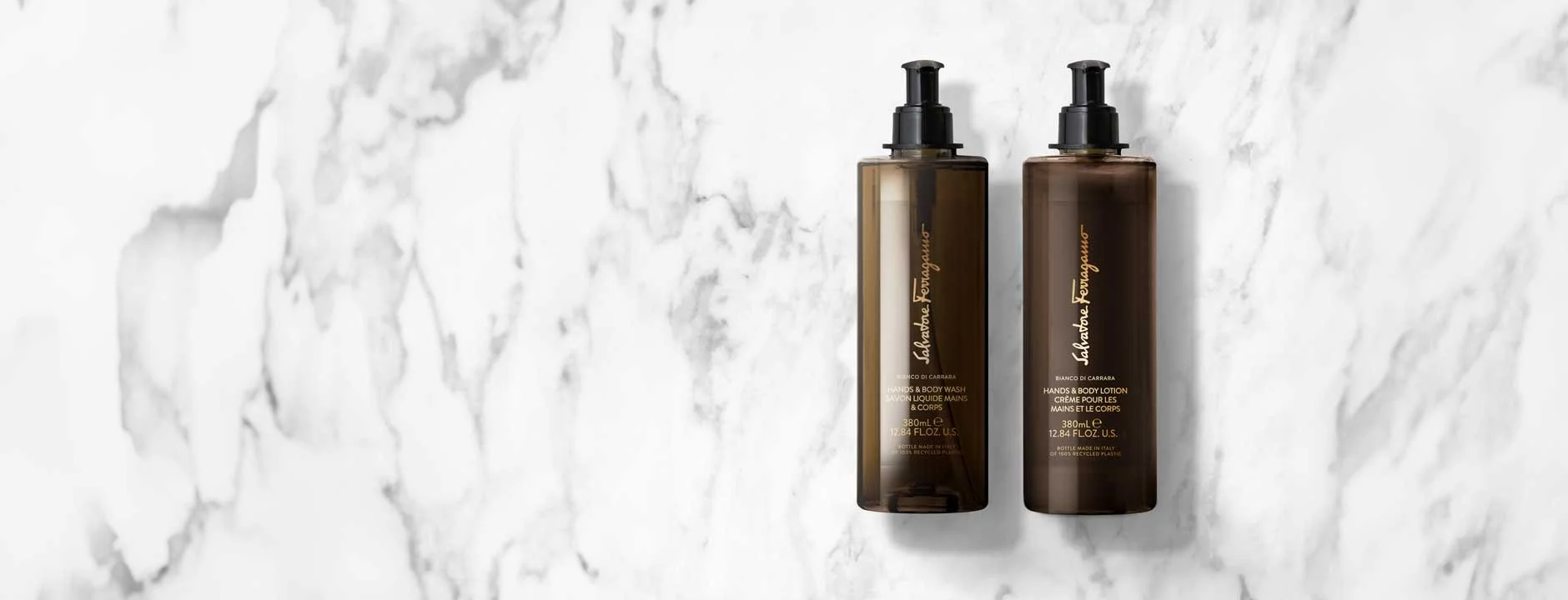 Two Salvatore Ferragamo Bianco di Carrara hand wash and body lotion bottles on white marble