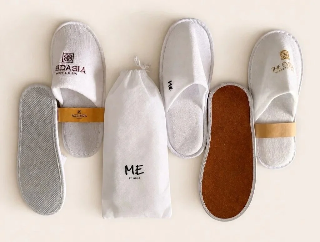Assortment of white hotel slippers and shoe insoles displayed on a light background