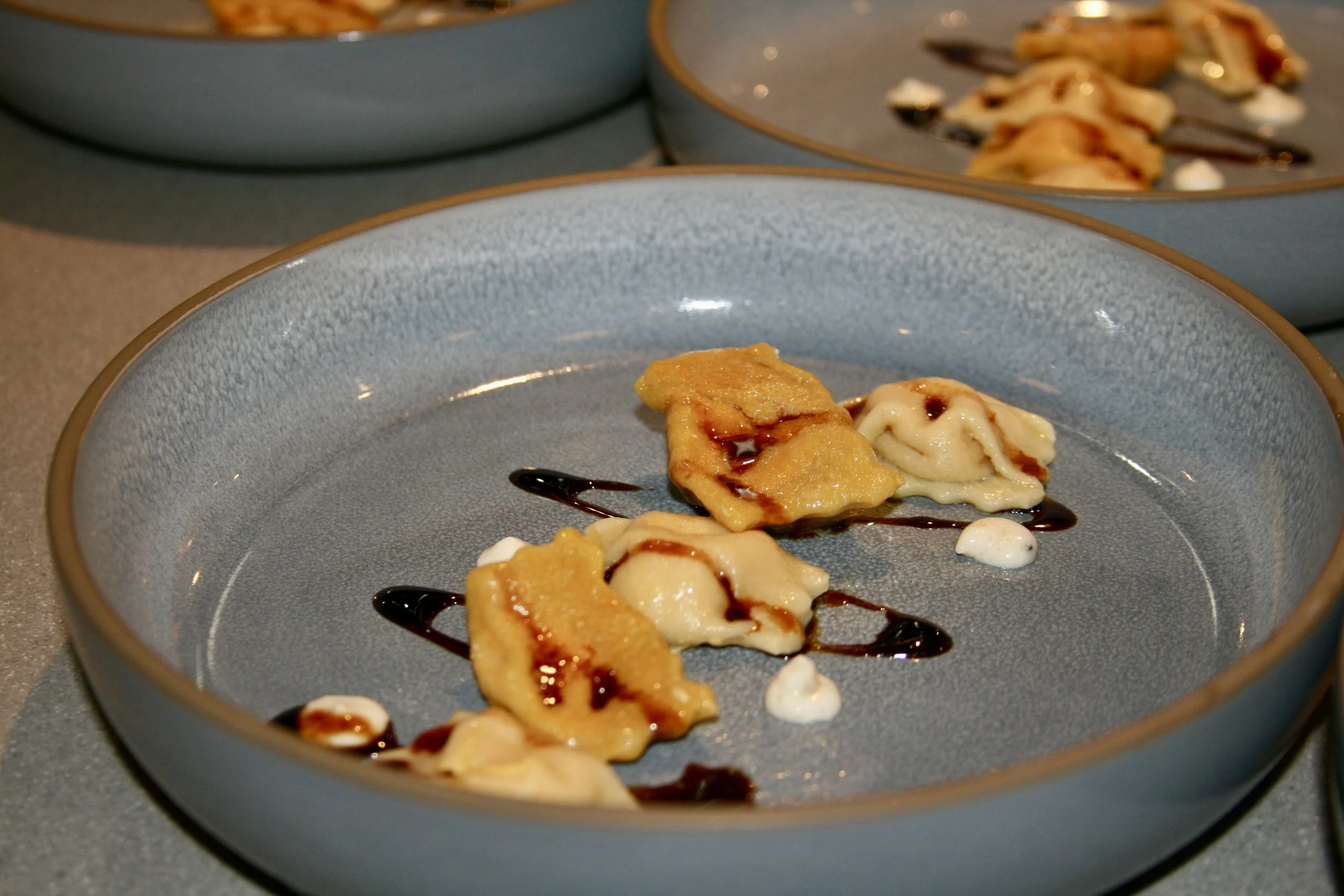 Chef plating gourmet dishes with precision in a kitchen.