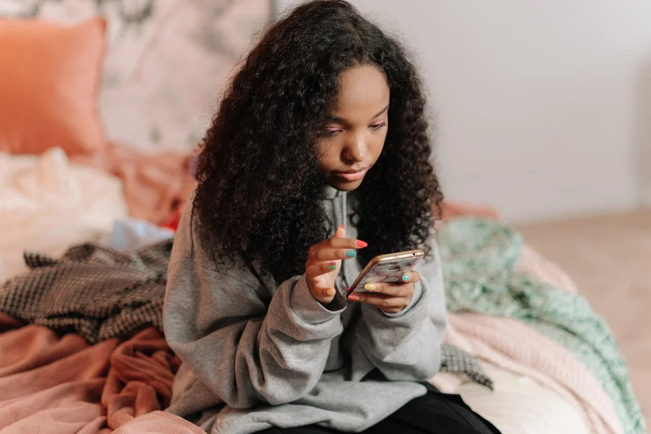girl-sitting-on-bed-using-cellphone