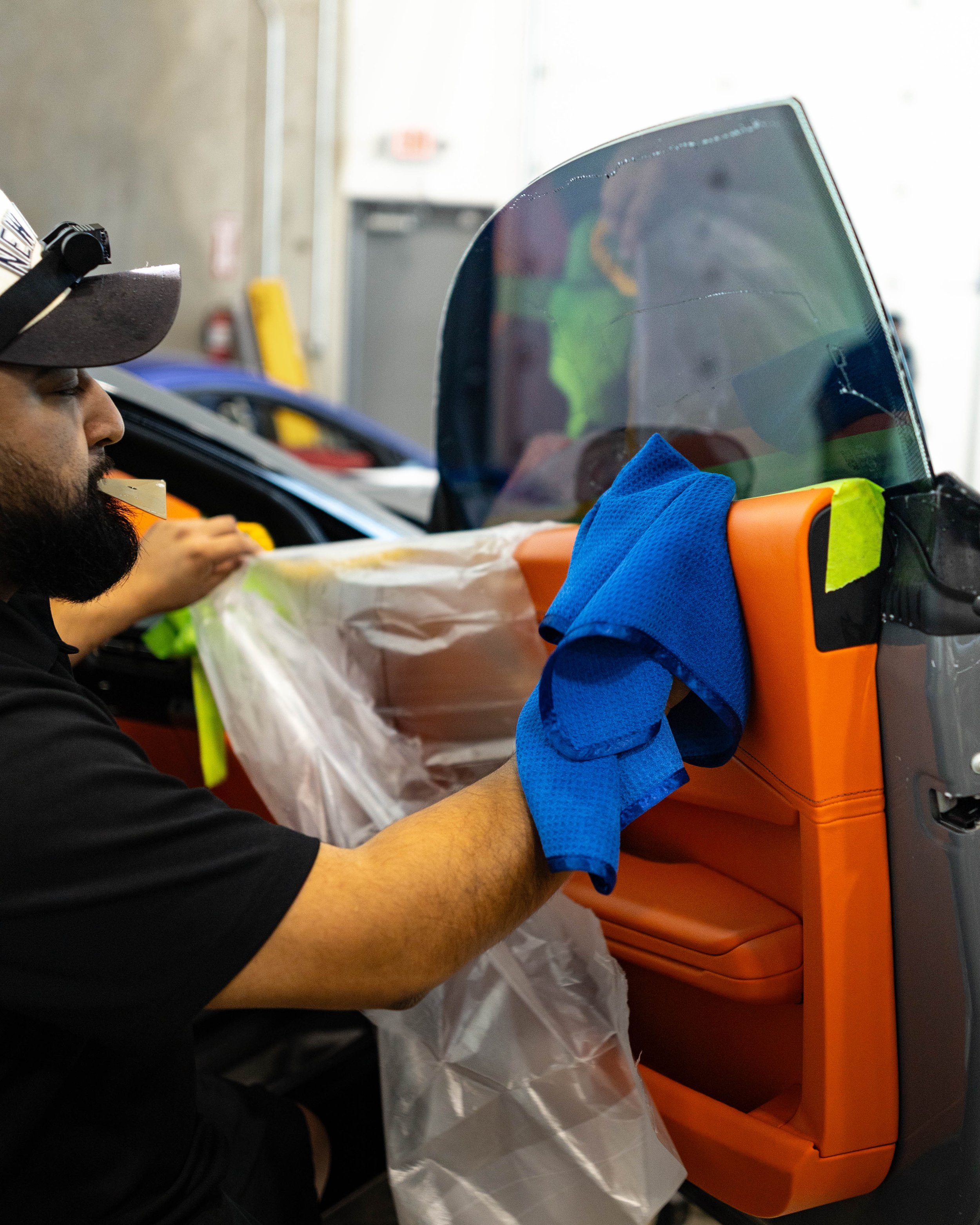 final steps of installing window tint ensuring the interior is completely protected and dried to prevent any damages as he removes a protective liner and wipes down the leather
