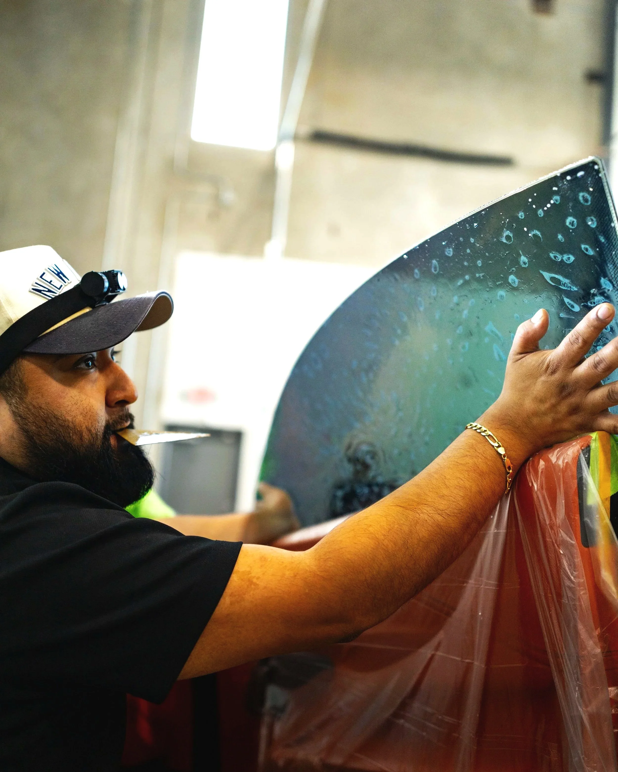 an installer lining up ceramic window tint to ensure a seamless look on all edges when squeegeed on with a protective liner to keep the car interior safe