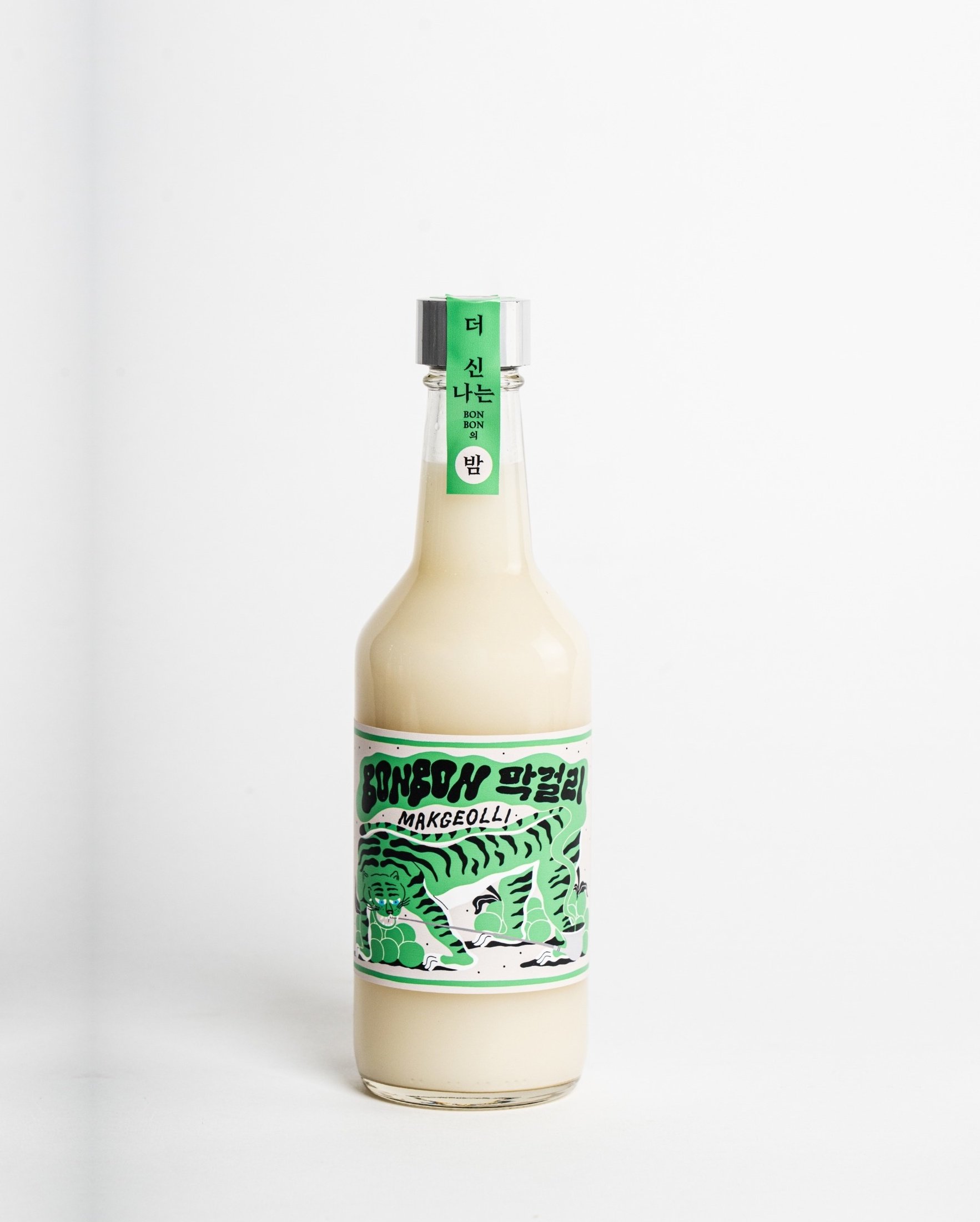 A glass bottle filled with a white liquid, featuring a colorful label with a green and black tiger illustration and Korean text.
