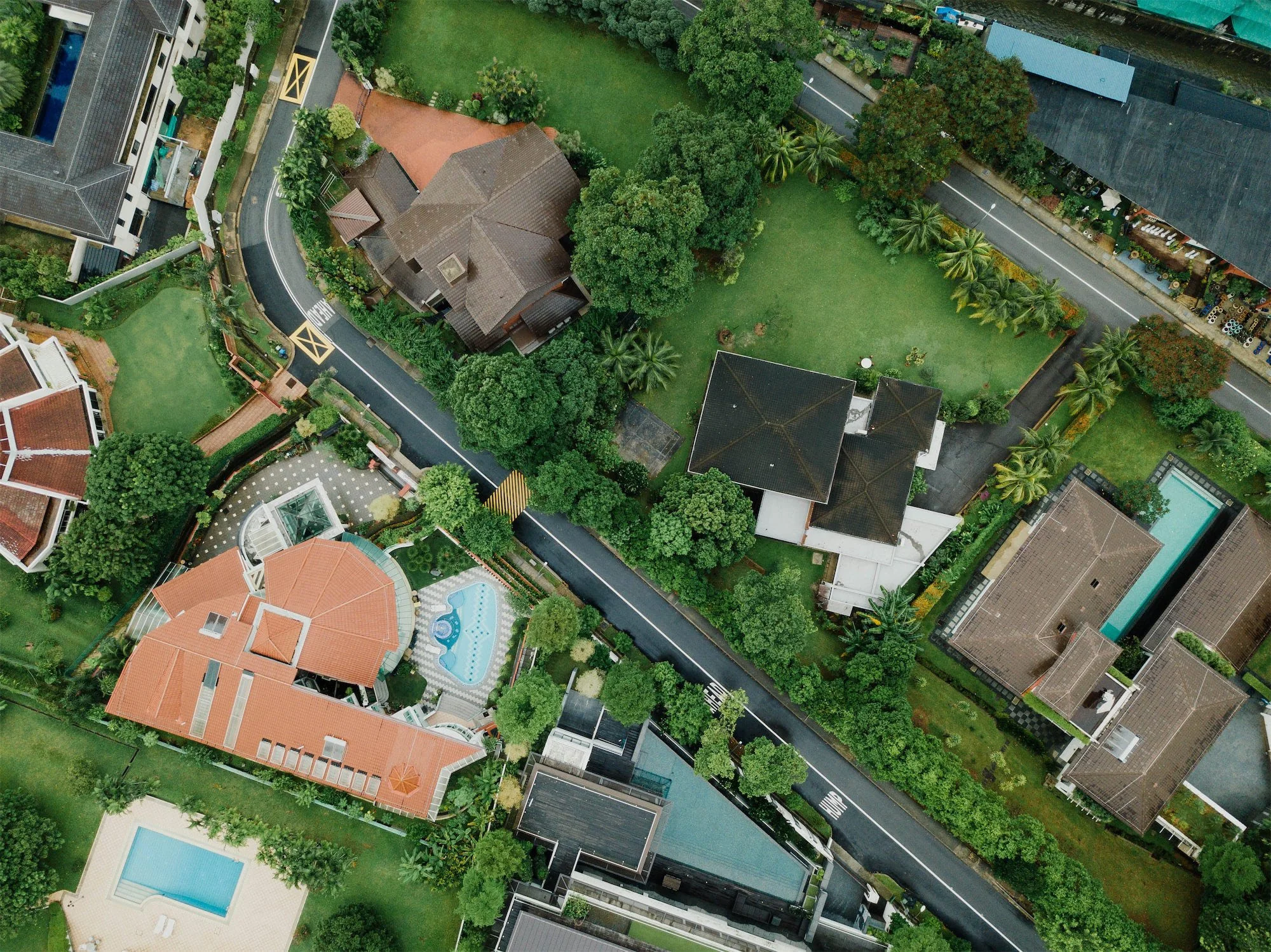 Fotografia aerea di un residence con case, piscine e giardini verdi.