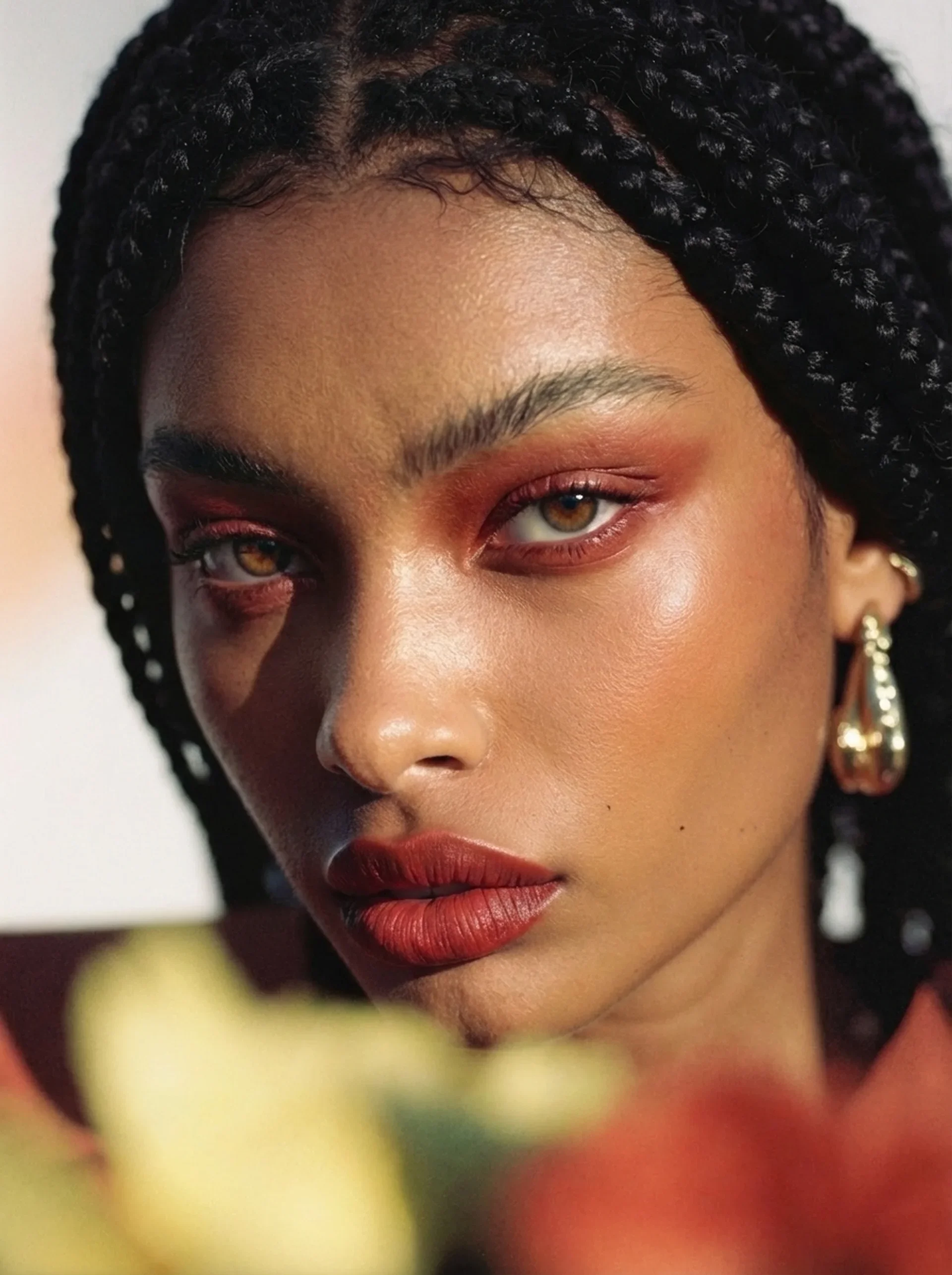 AI campaign visual jewelery brand:Close-up of a woman's face featuring her brown eyes, bold red lipstick, and intricately styled braids in her hair.