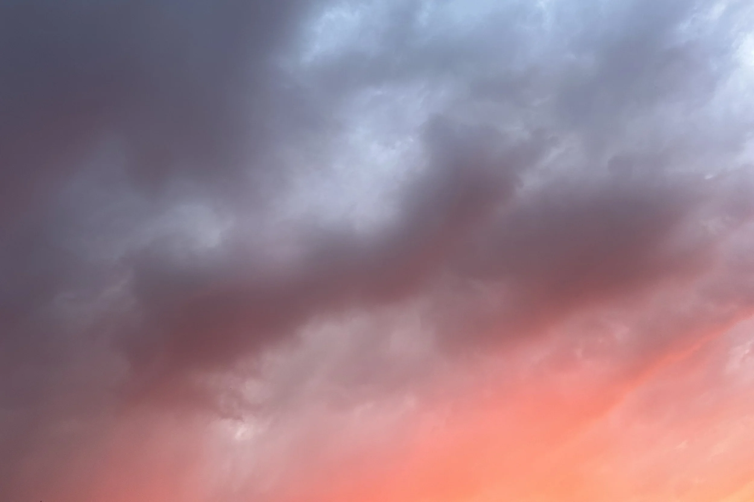 Layered blue-gray clouds melting into a coral sunset glow