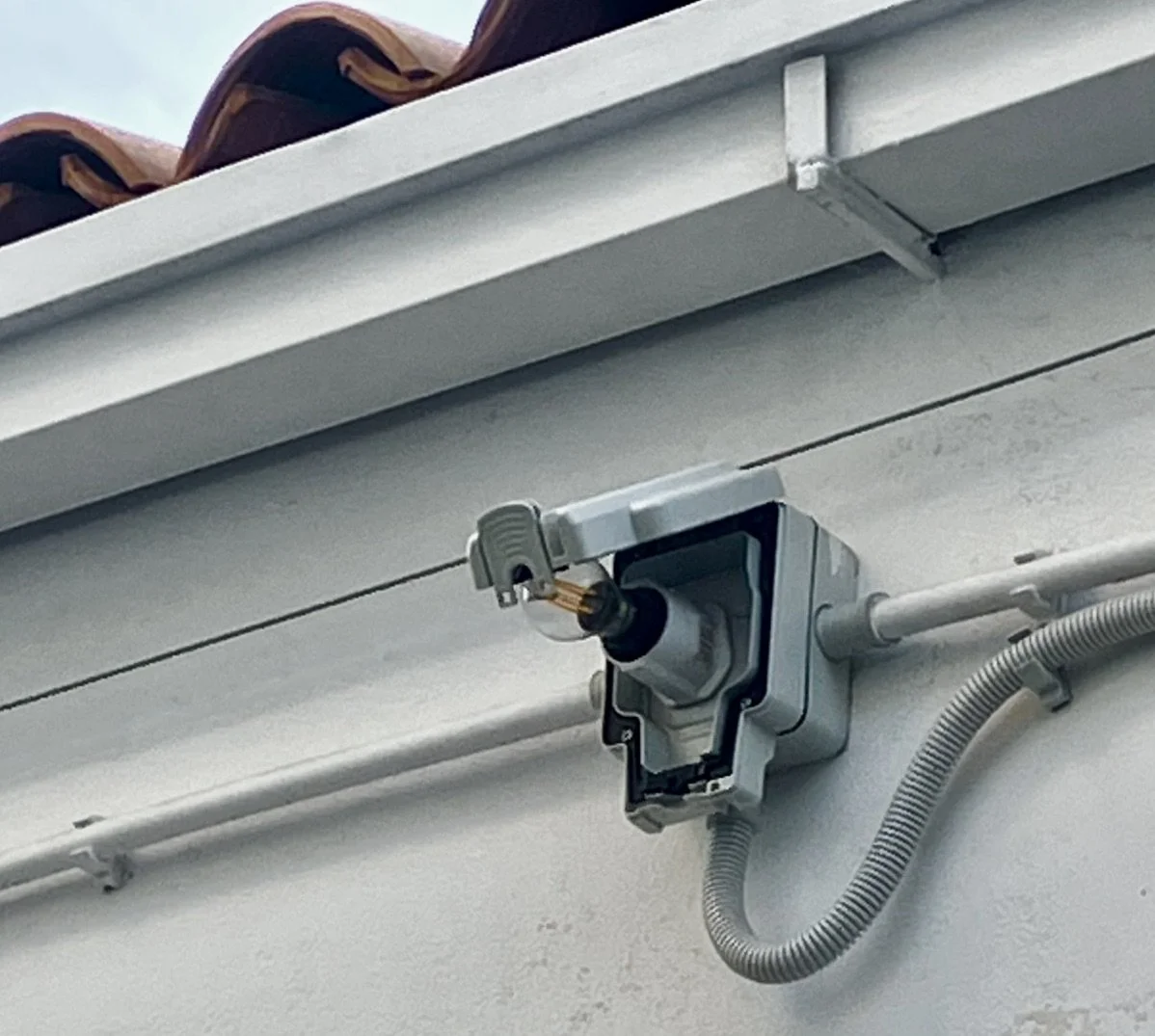 Close-up of an exterior security camera mounted on a building with visible wiring and pipes.