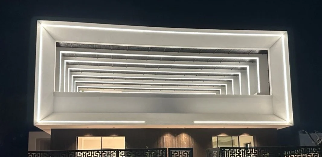 Exterior view of a modern building with illuminated rectangular archways in a repeating pattern at night.