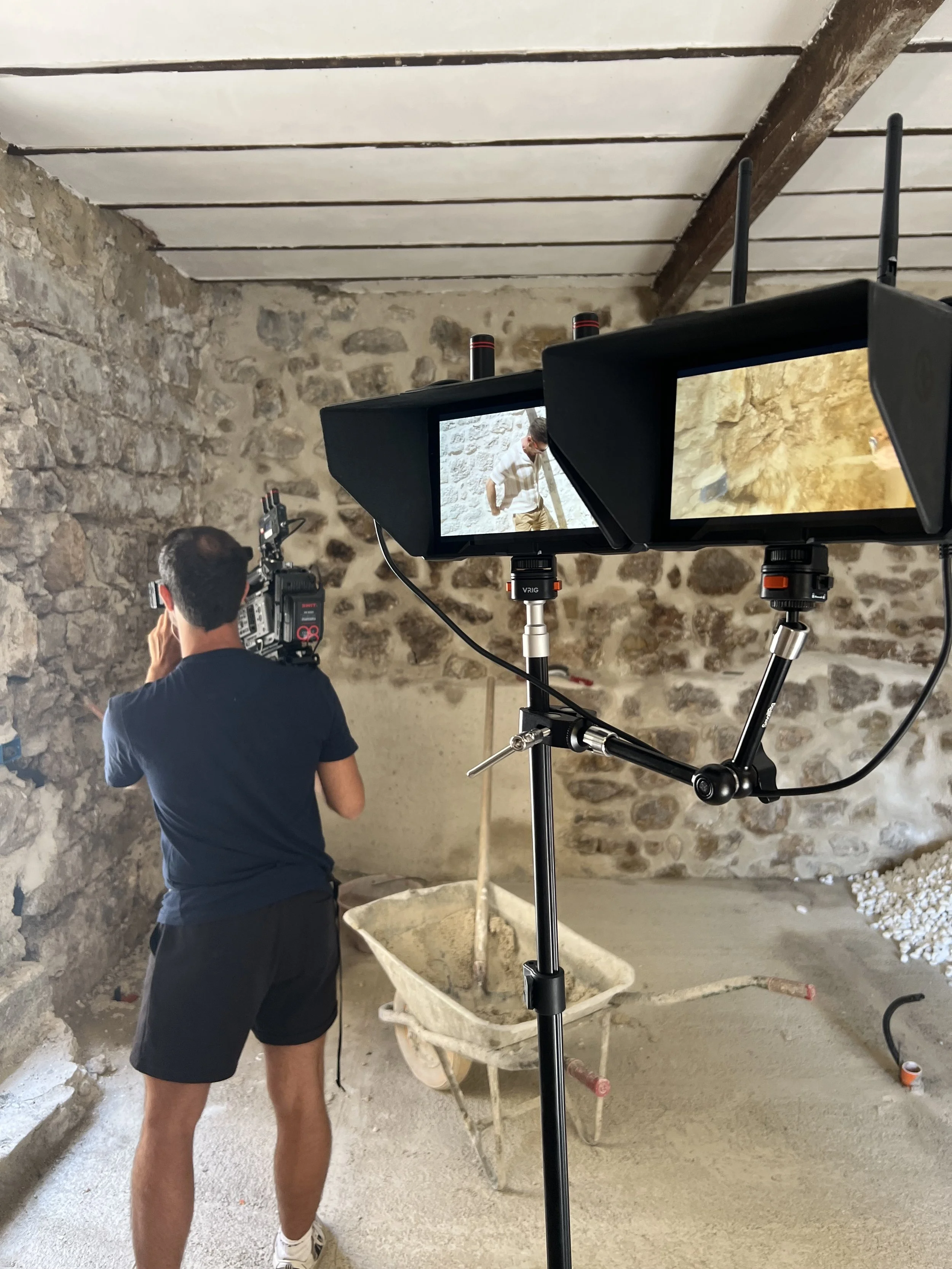 Camera operator and production monitors inside a stone building under renovation