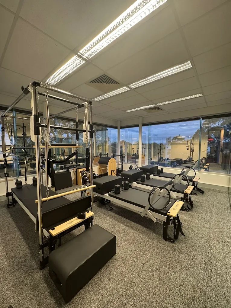Pilates reformer machines in a fitness studio with large windows showing an outdoor view.