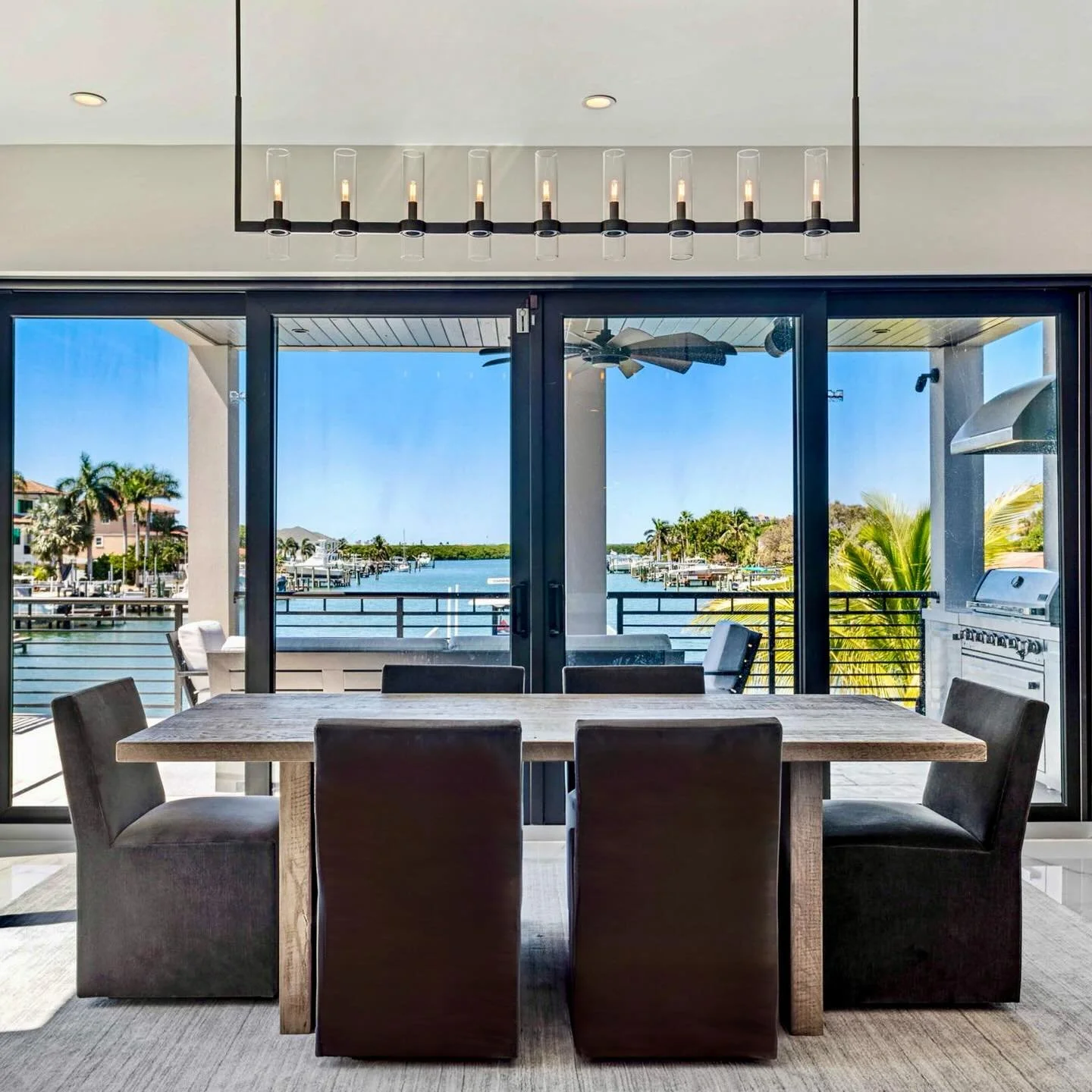 Dining with a view! The linear chandelier brings the drama, the wood table adds warmth, and those charcoal velvet chairs? Pure luxe. Oh, and the view&rsquo;s not bad either 😉