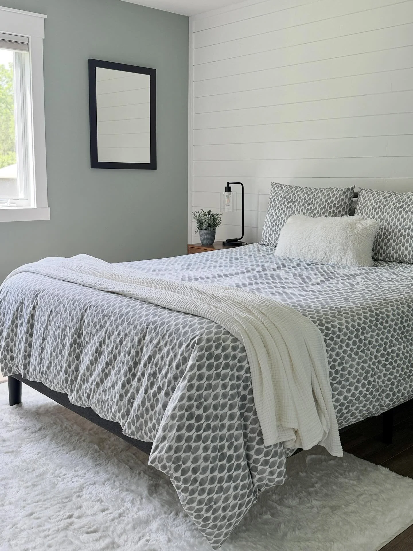 In this serene setup, we played with texture to create warmth and depth without straying from a soft, neutral palette: 
&bull; Shiplap accent wall for subtle structure
&bull; Matte sage paint for a calming contrast
&bull; Patterned bedding for gentle