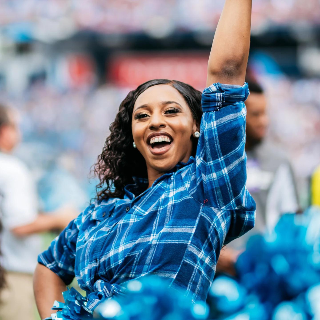 Cheerleader in plaid shirt smiling at a sports event