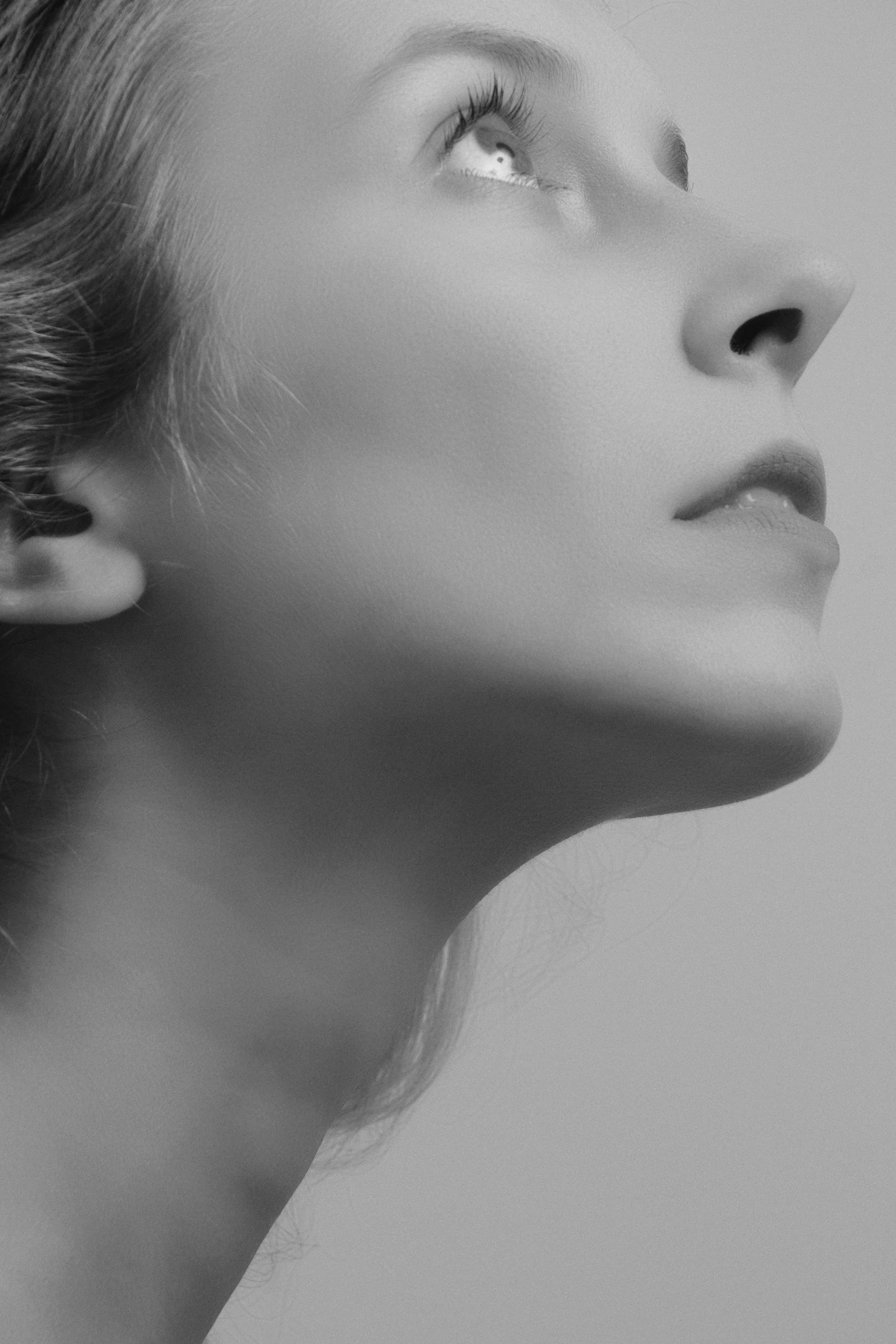 Close-up black and white photo of a woman's side profile showing her nose, lips, and part of her eye, with soft lighting emphasizing facial features.
