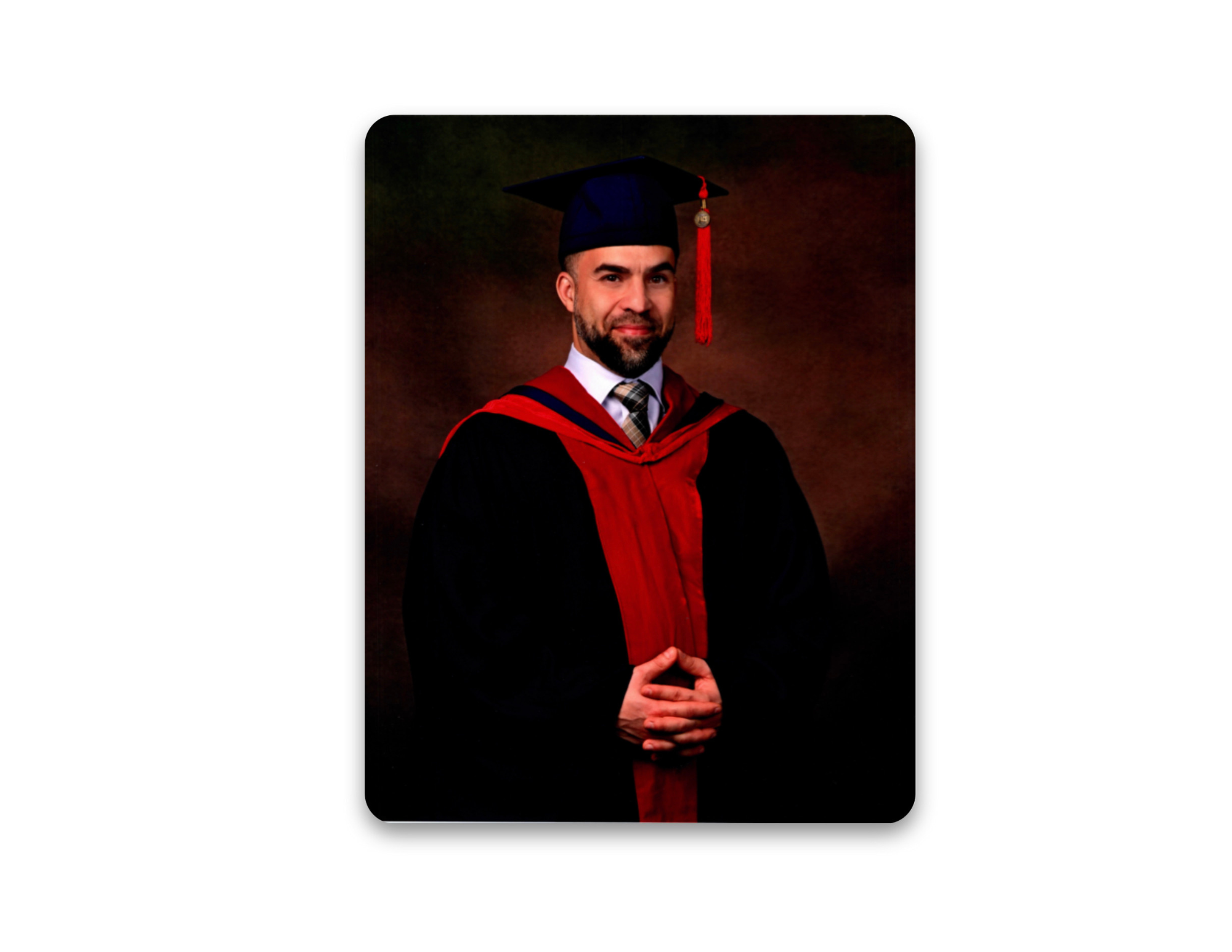 A man in a graduation cap and gown, with a red and black academic hood, standing against a dark background.