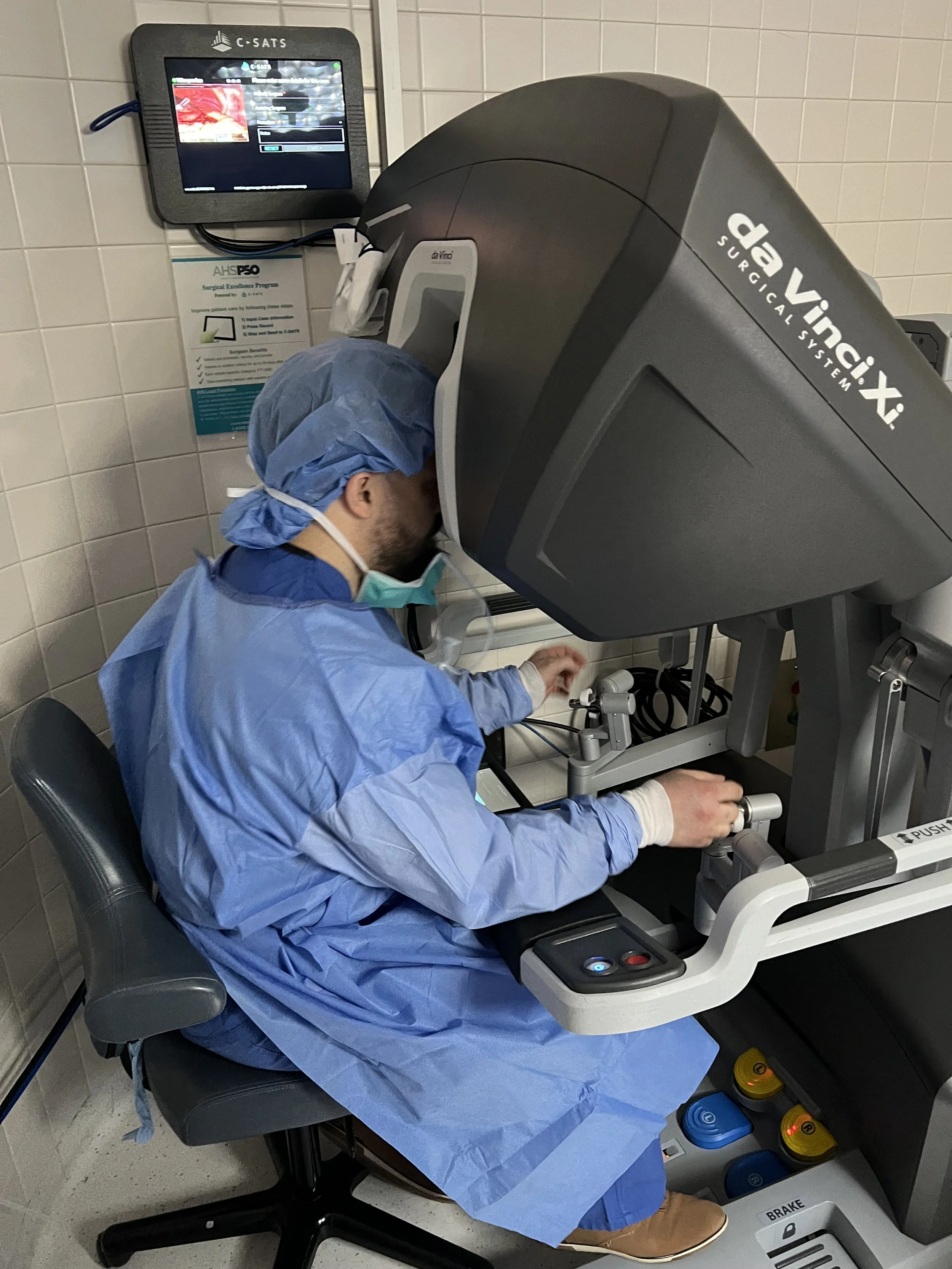 Medical professional using a da Vinci surgical system in a hospital room.