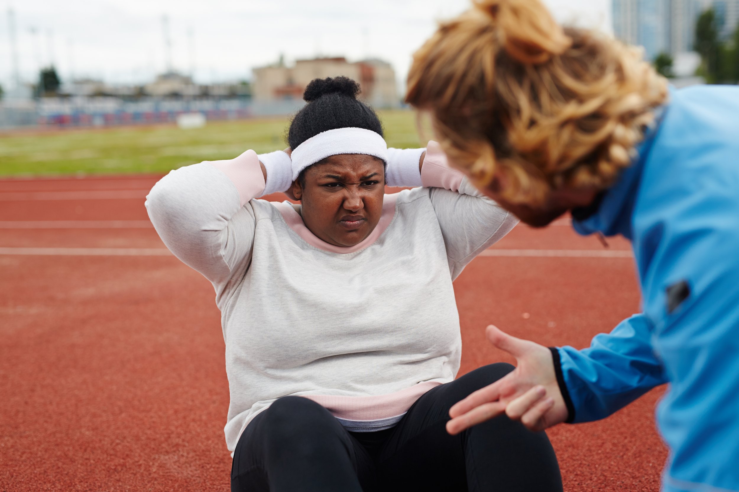 Photo of an overweight woman working hard with a fitness coach to achieve weight loss goals.