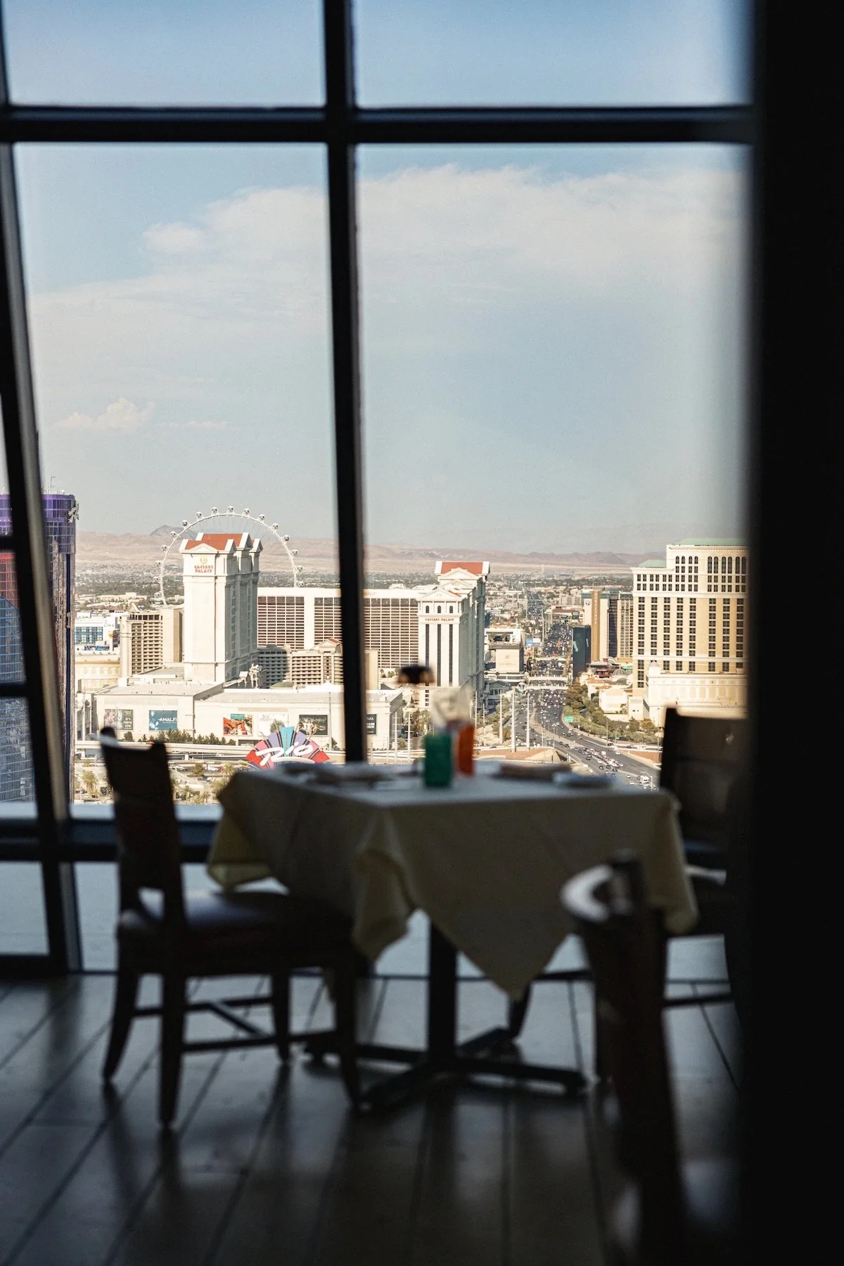 A stunning view of the Las Vegas skyline seen through a restaurant window behind a client's elegant tablescape, photographed by the best digital marketing agency in Las Vegas.