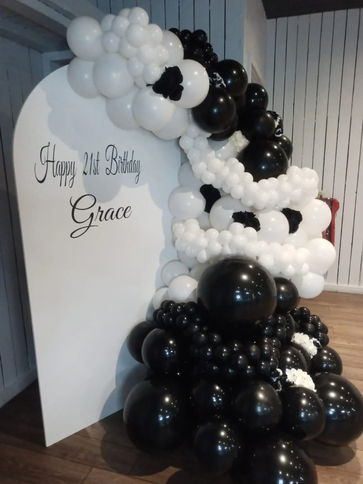 Black and white balloon arch and backdrop with a sign that reads 'Happy 21st Birthday Grace'