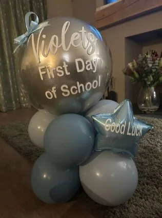 Set of silver and blue balloons with personalized message for a child's first day of school, including a star-shaped balloon that says "Good Luck".