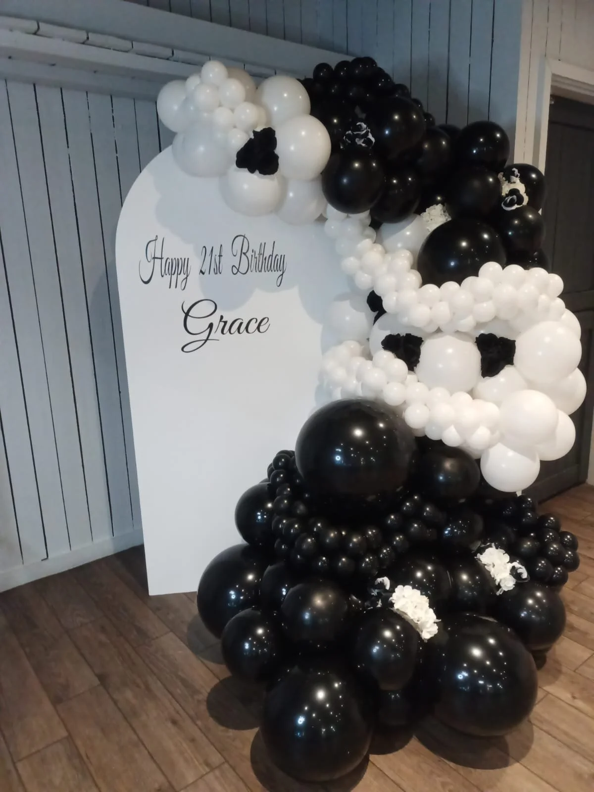 Balloon arrangement with black and white balloons surrounding a sign that says, 'Happy 21st Birthday Grace'.