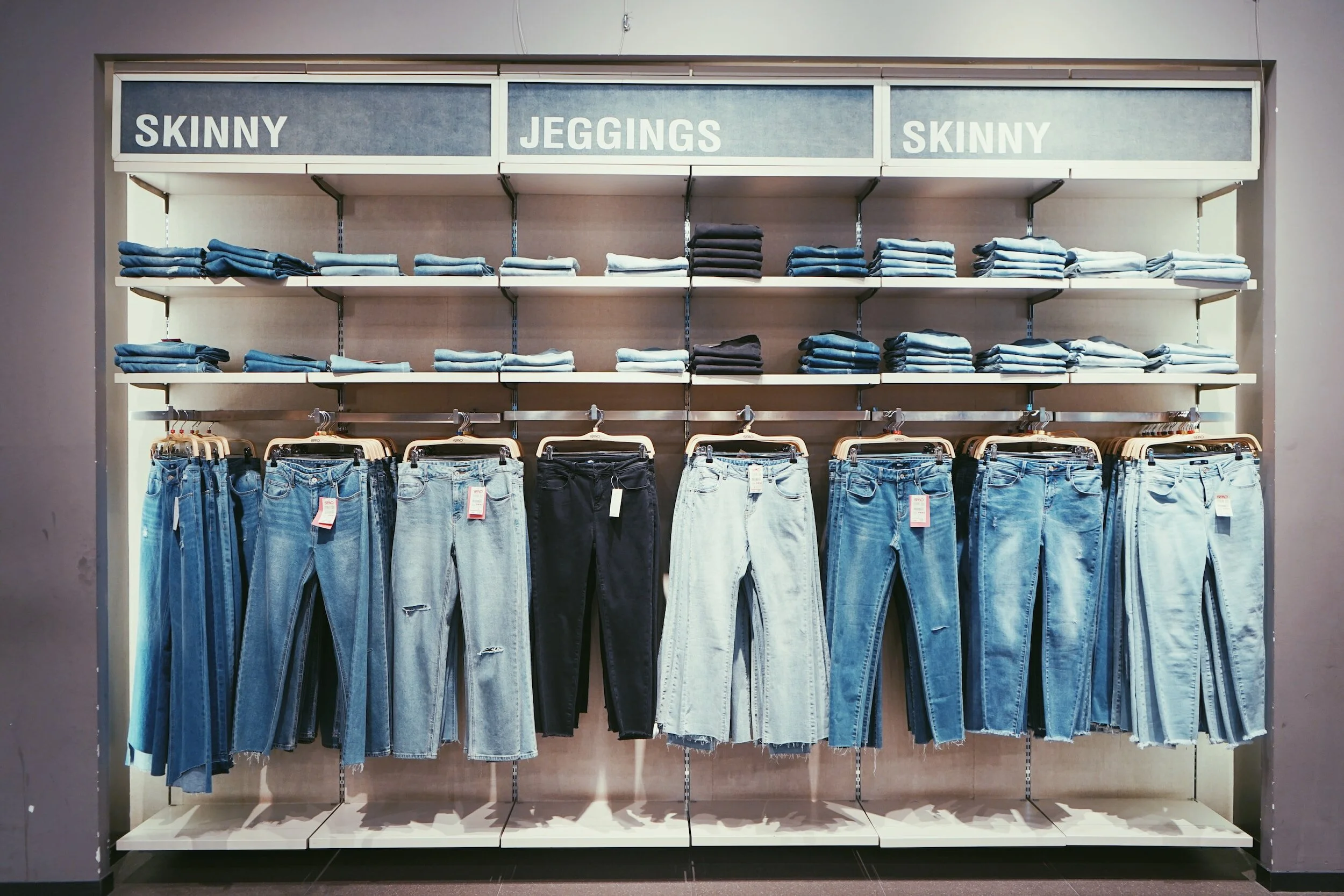 A variety of jeans both skinny and jeggings are up on clothing racks.