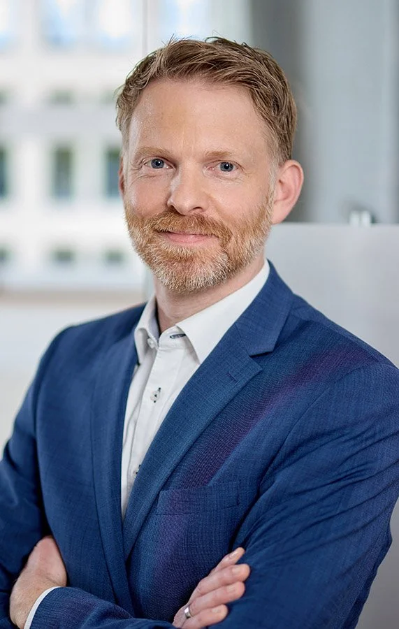 Geschäftsführer in blauem Anzug schaut zuversichtlich in dir Kamera