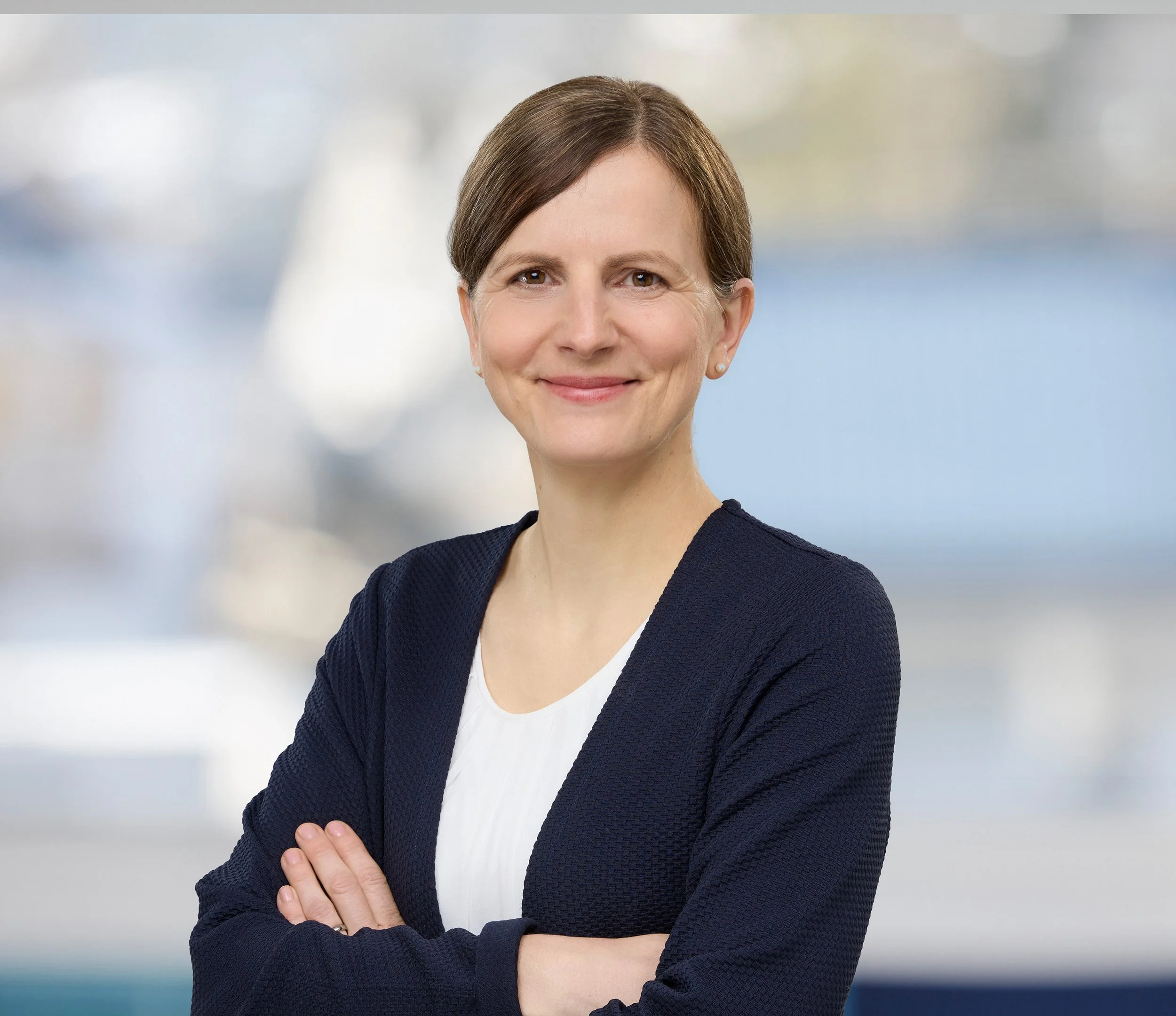 Mitarbeiterin aus dem Pflegebereich vor hellem Hintergrund. Mitarbeiterportrait