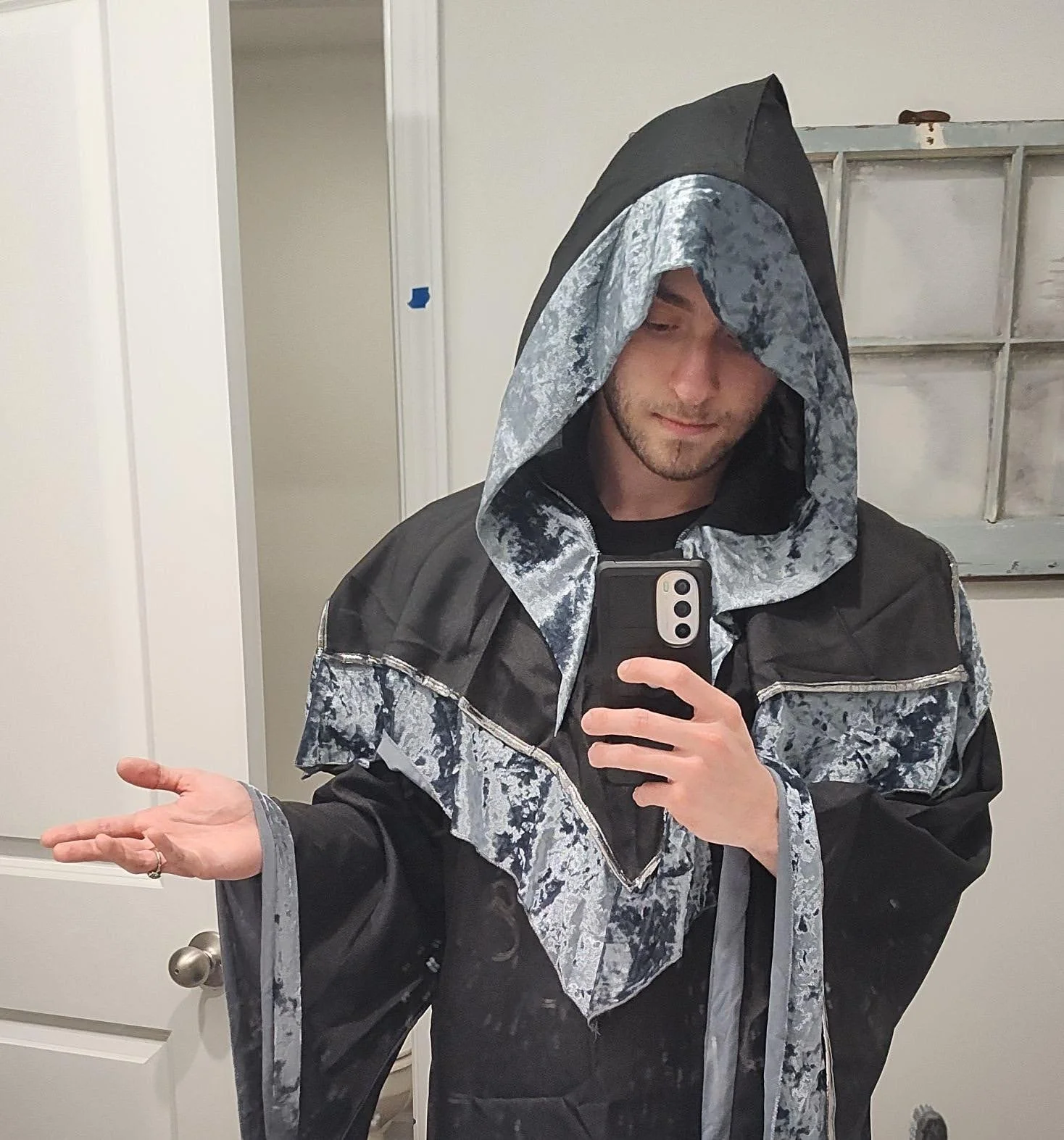 A man taking a mirror selfie wearing a black and gray patterned wizard robe.