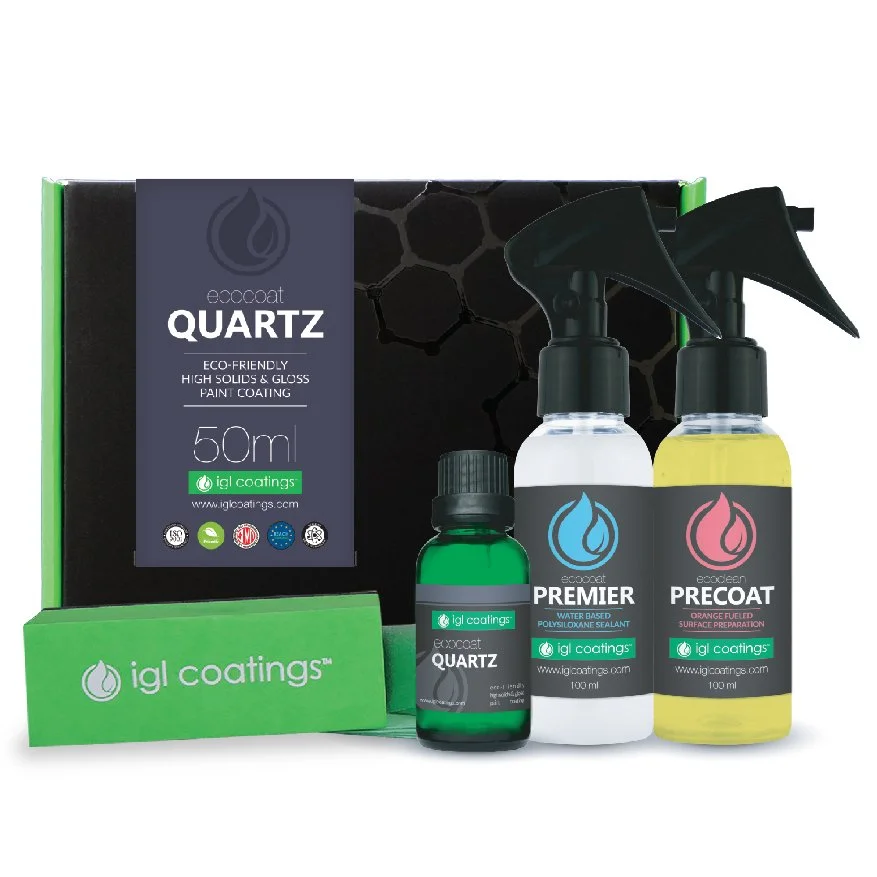 Set of eco-friendly car coating products, including spray bottles labeled 'PREMIER' and 'PRECOAT', a small bottle labeled 'QUARTZ', and a green box with 'igl coatings' branding.