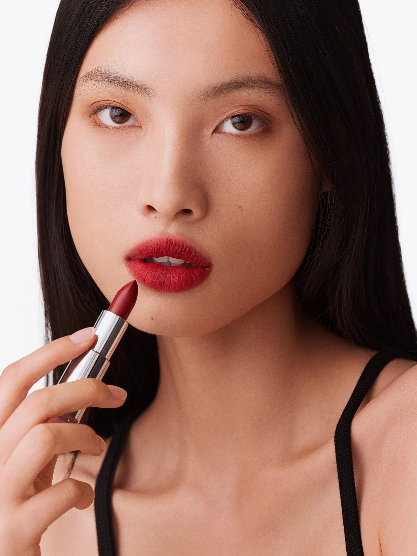Model applying red lipstick beauty shot by a beauty photographer working in London and Europe