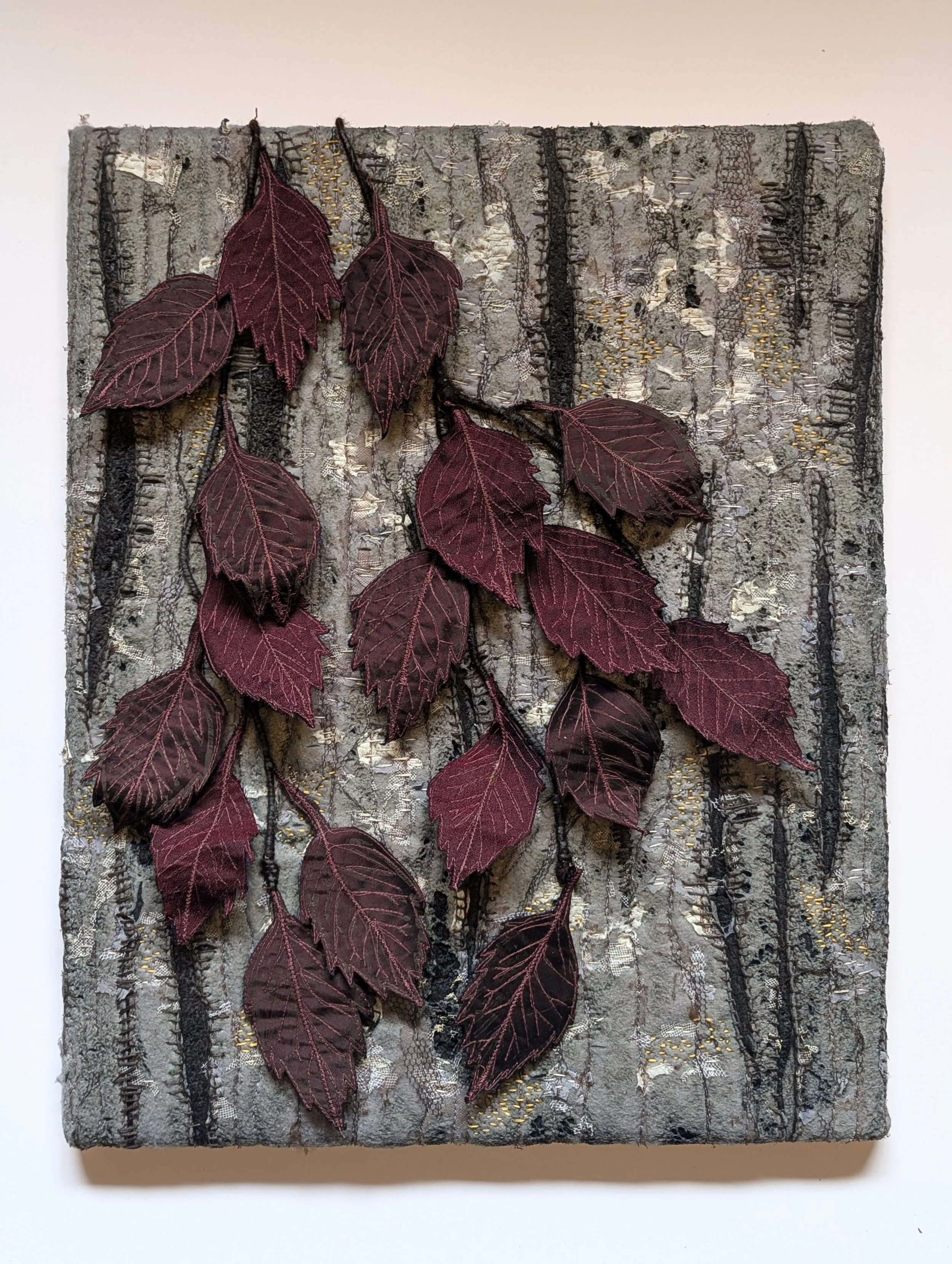 Mixed media artwork featuring a textured background of tree bark, overlaid with a branch of dark burgundy silk leaves.