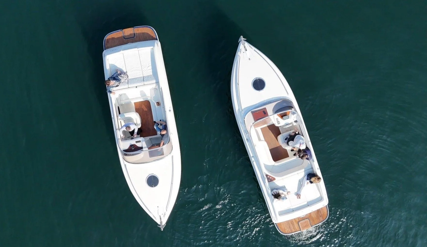 Due barche a vela con persone a bordo navicano sull'acqua blu.