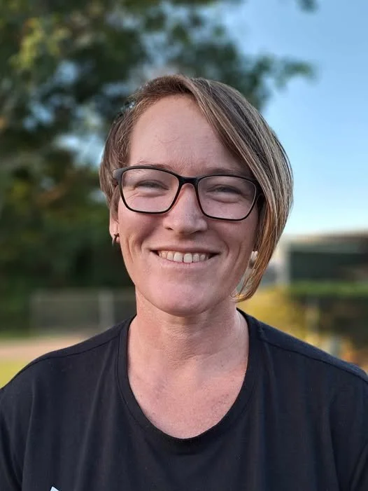 A photo of Renay Thomas a speaker at Thrive 2026 conference woman with short brown hair, glasses, and earrings smiling outdoors on a sunny day.