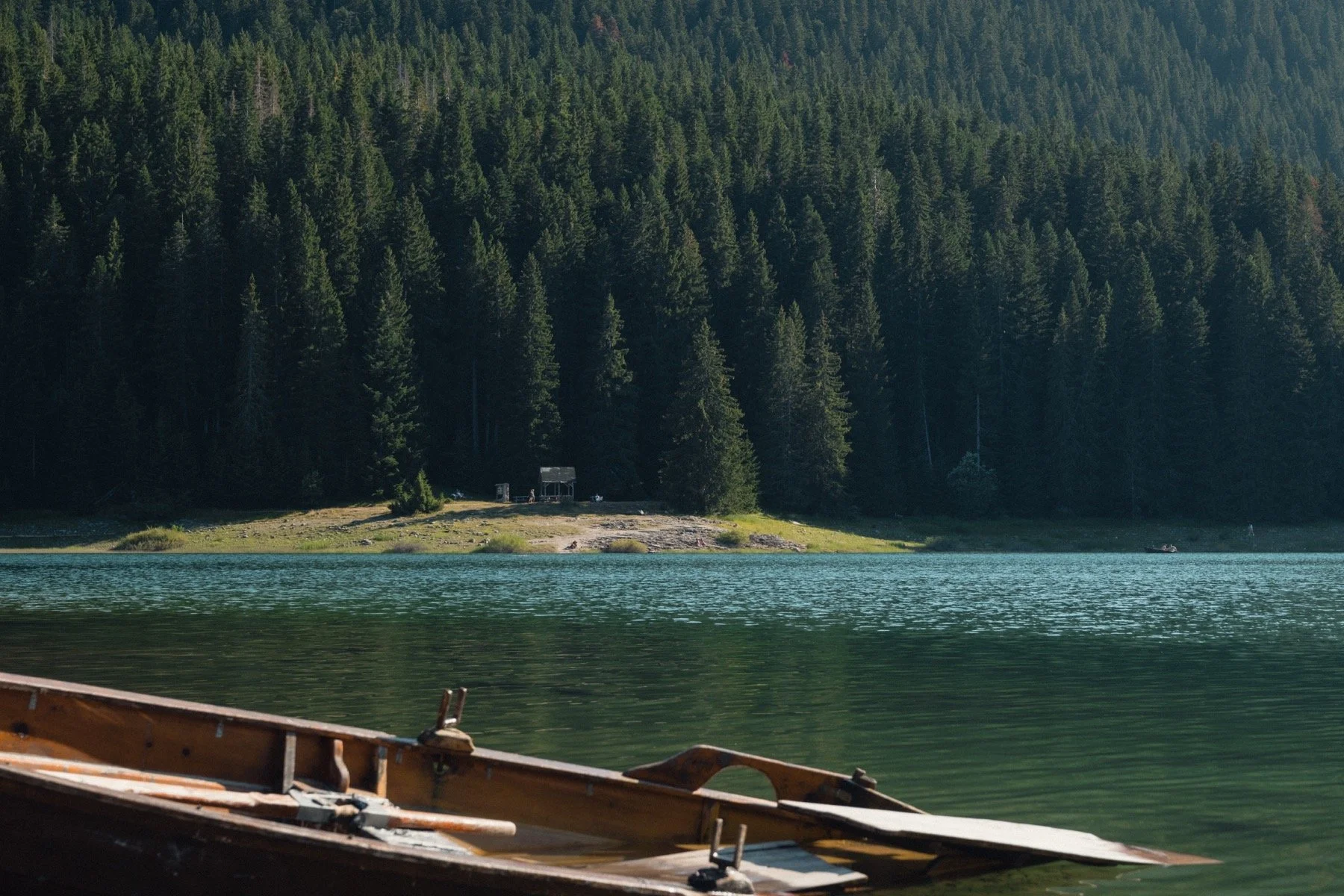 Wooden boats beside a quiet lake and forest, photographed by Russell Baxter.