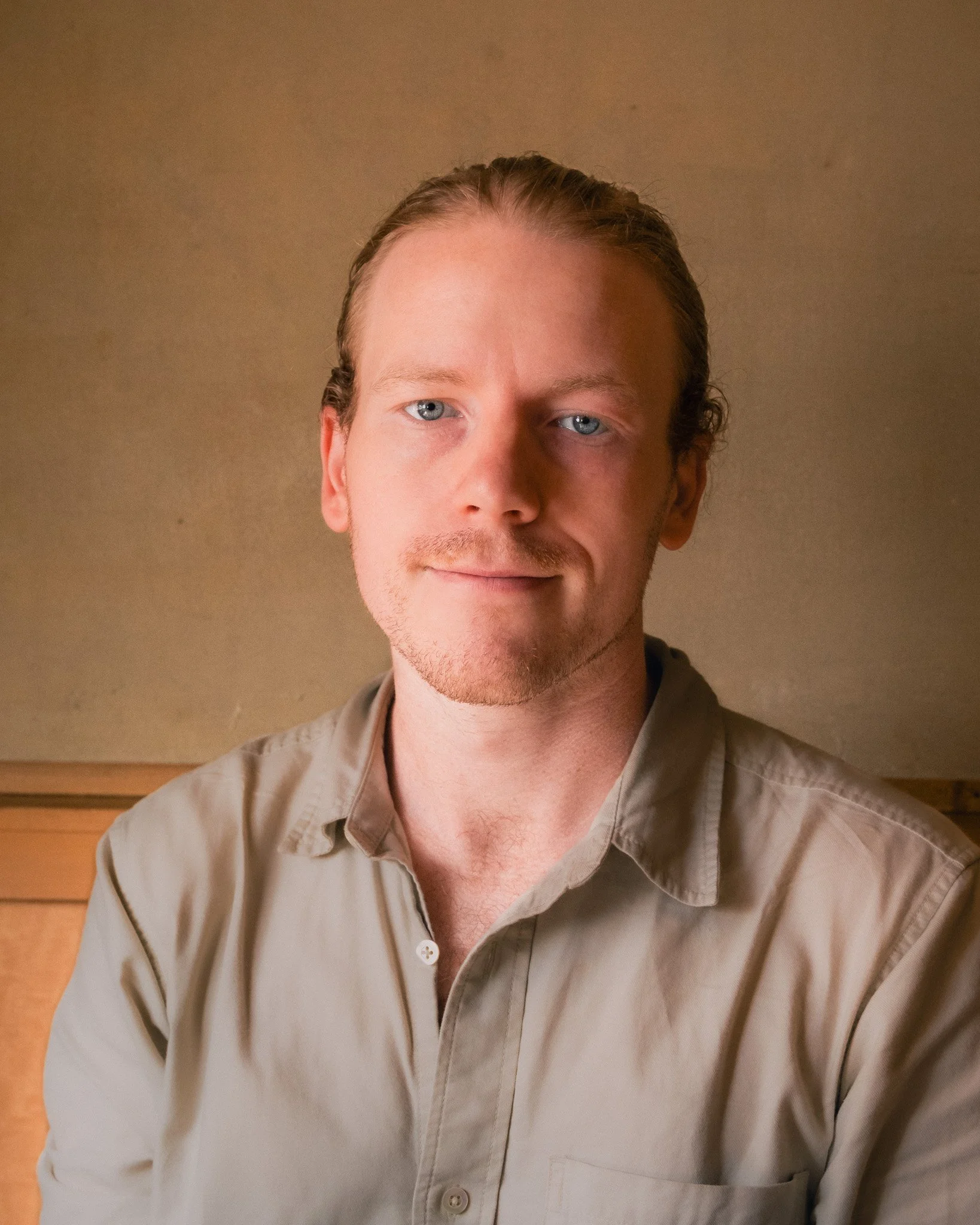 Color portrait of Russell Baxter, LPC-MHSP, looking at the camera in a taupe shirt against a warm tan wall.