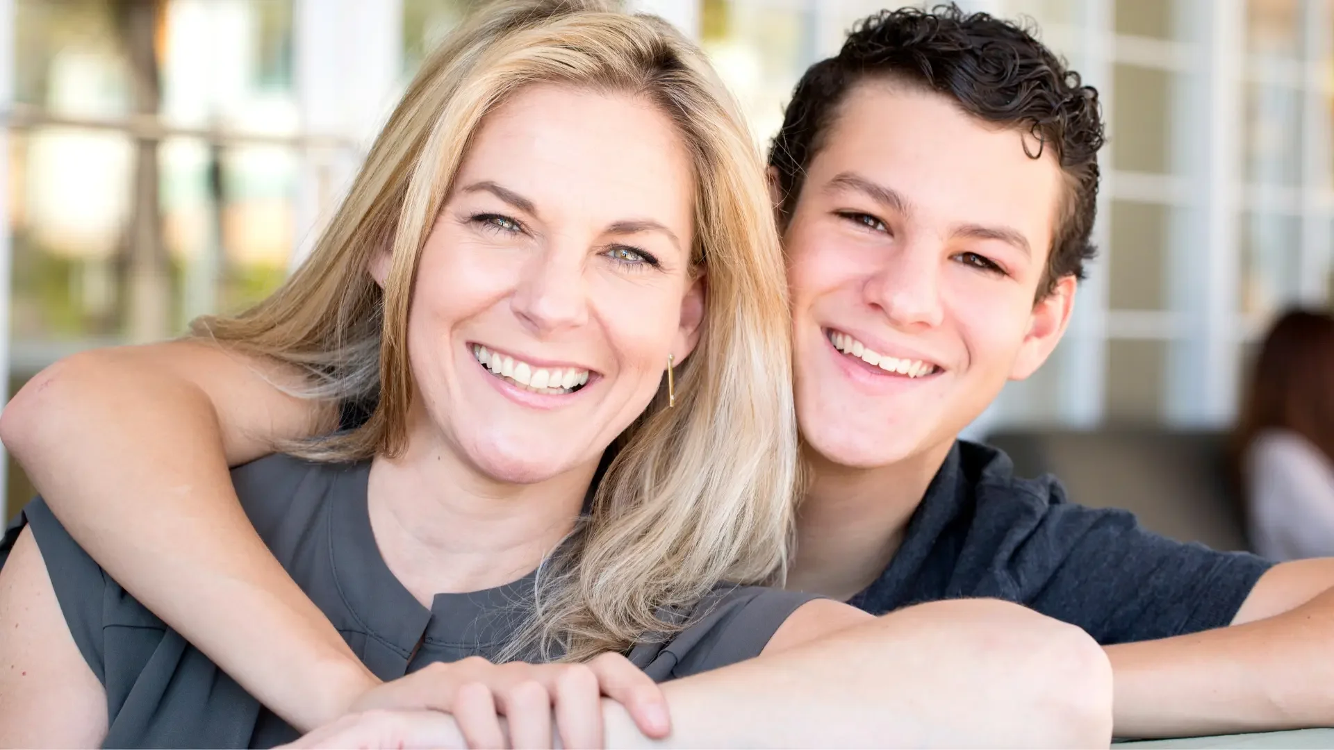 A smiling mother and teenage son sitting close together, representing the parent-teen connection discussed in Watershed Counseling's blog on adolescent therapy in Jackson, MS.