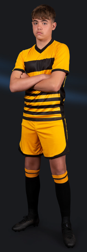 Young male soccer player in yellow and black uniform standing with arms crossed against a dark background.