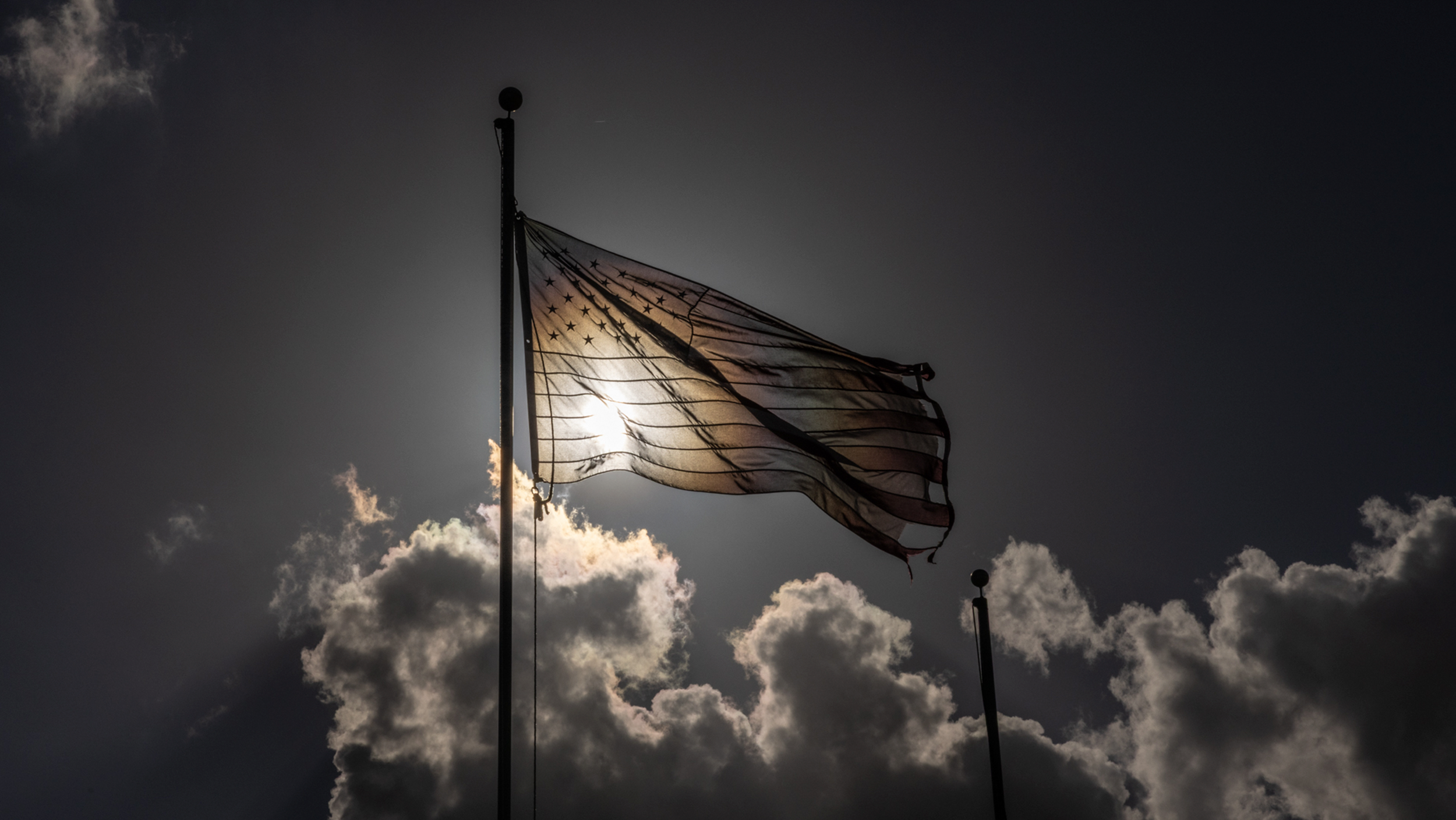 An American flag against a dark, cloudy sky