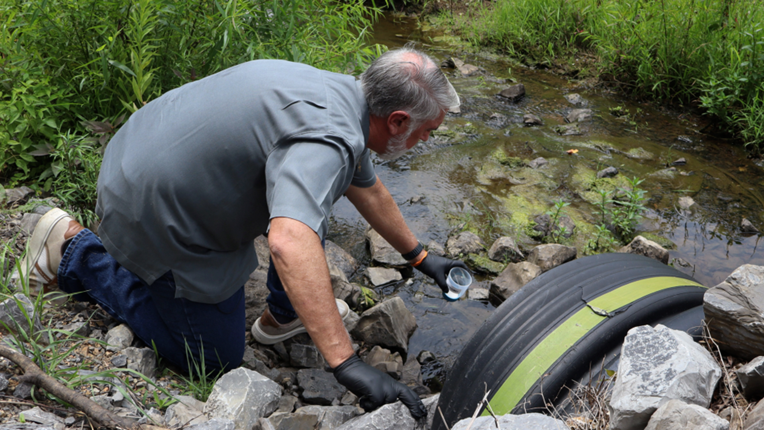 A man inspecting a polluted creek