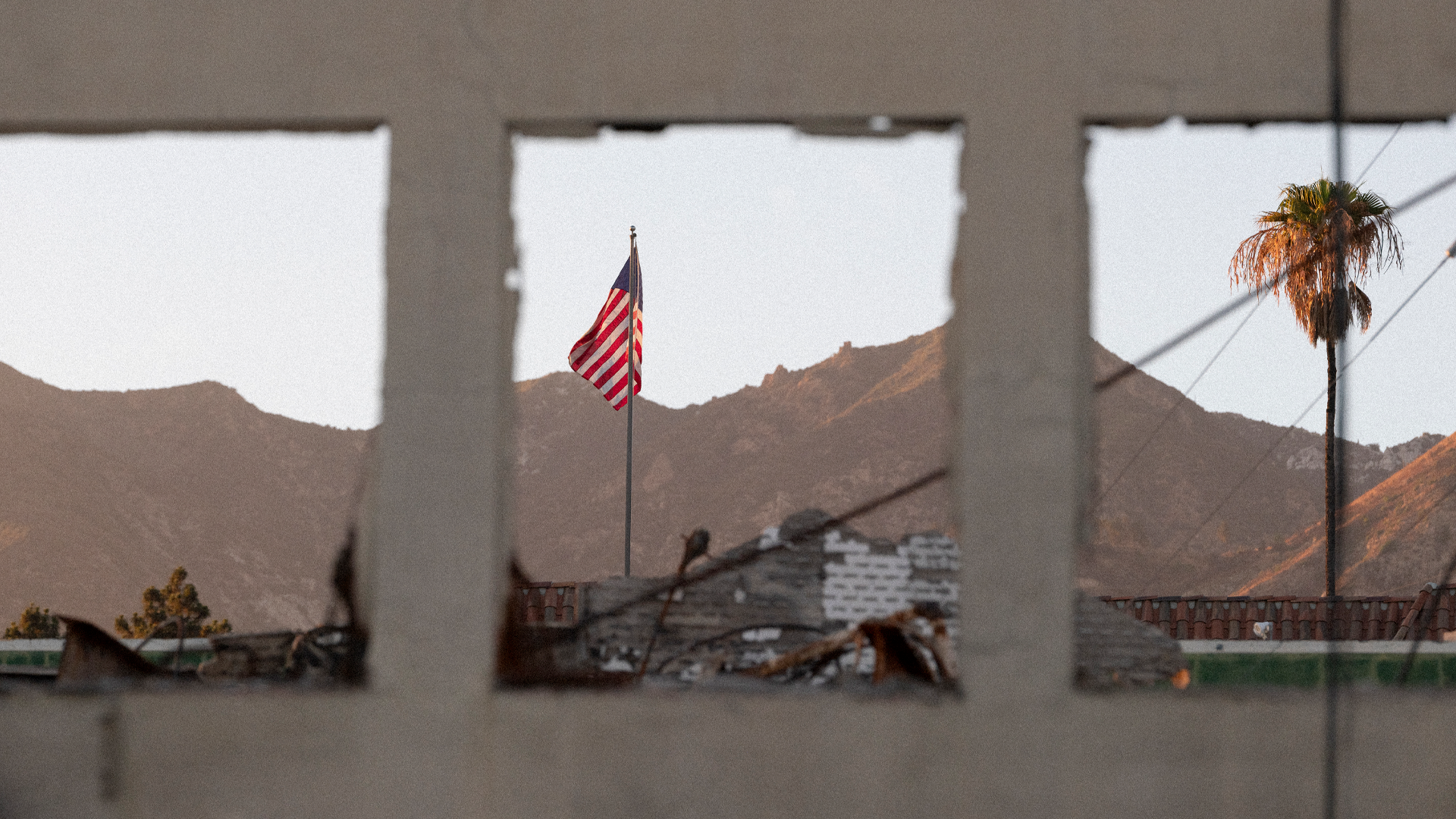 A burned-out building with an American flag beyond