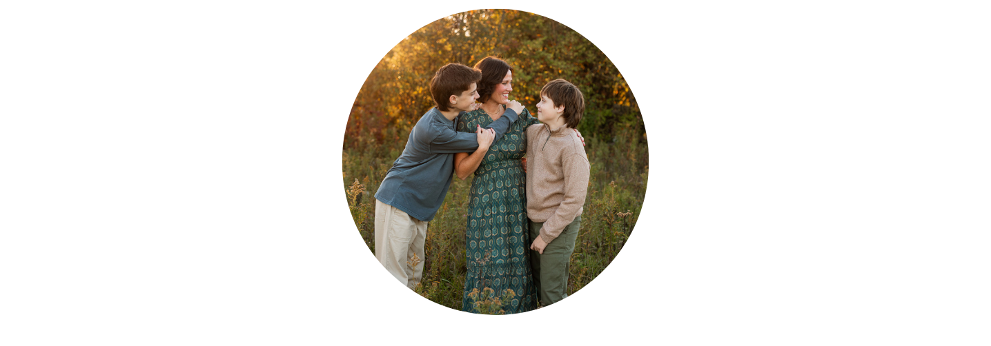 Group of three people smiling in an outdoor setting with autumn foliage.