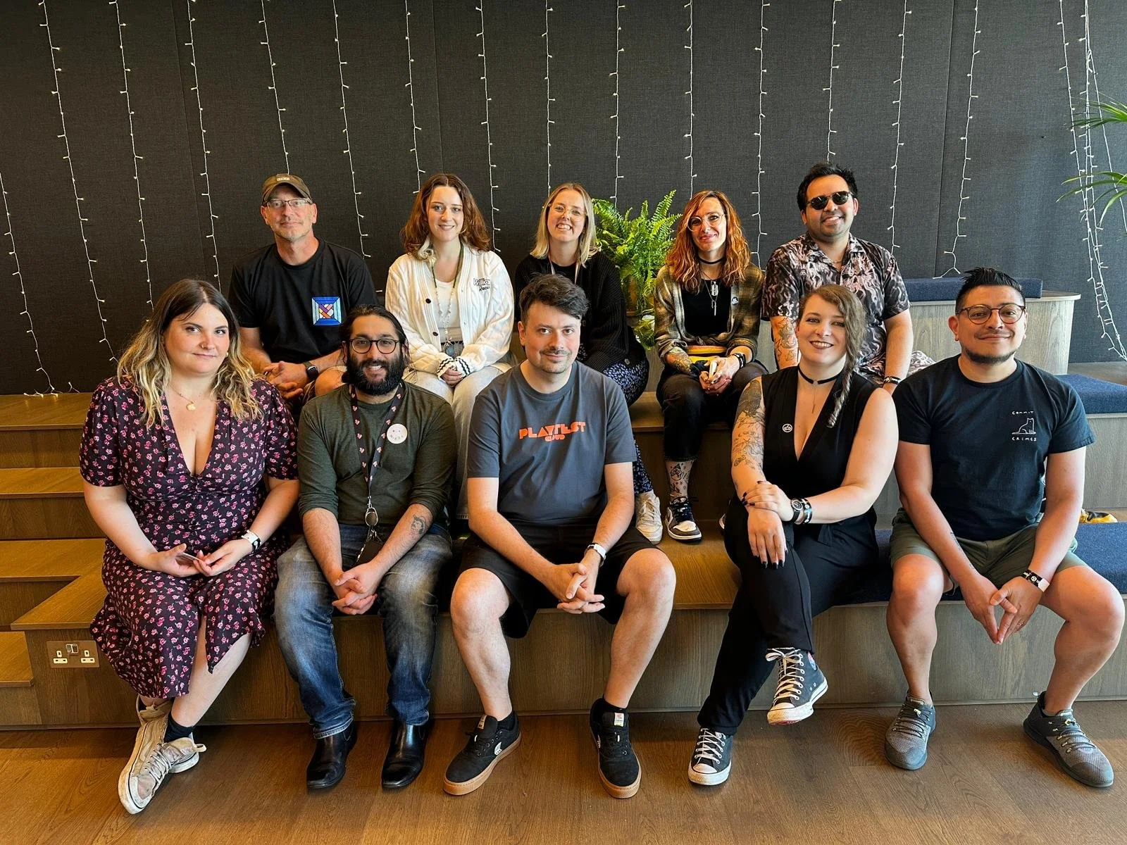 10 people sit on bleacher seating, smiling at the camera.