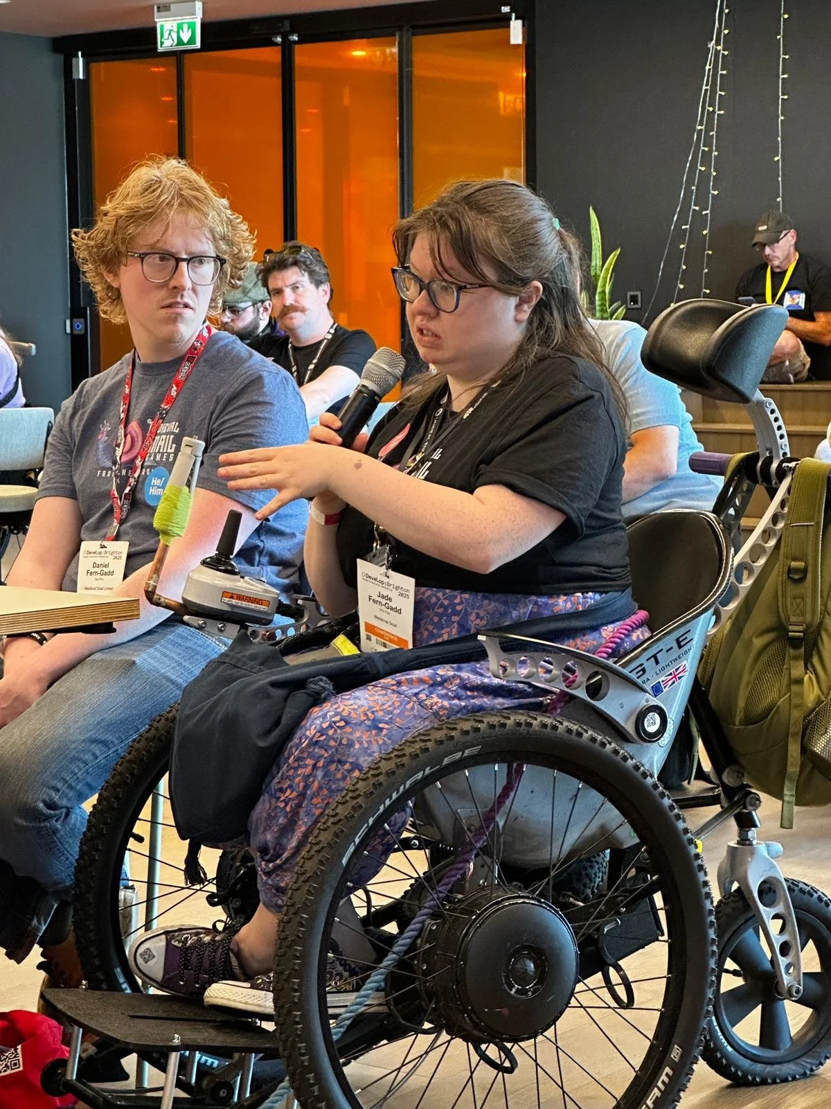 A person in a wheelchair holds a mic and is asking a question.