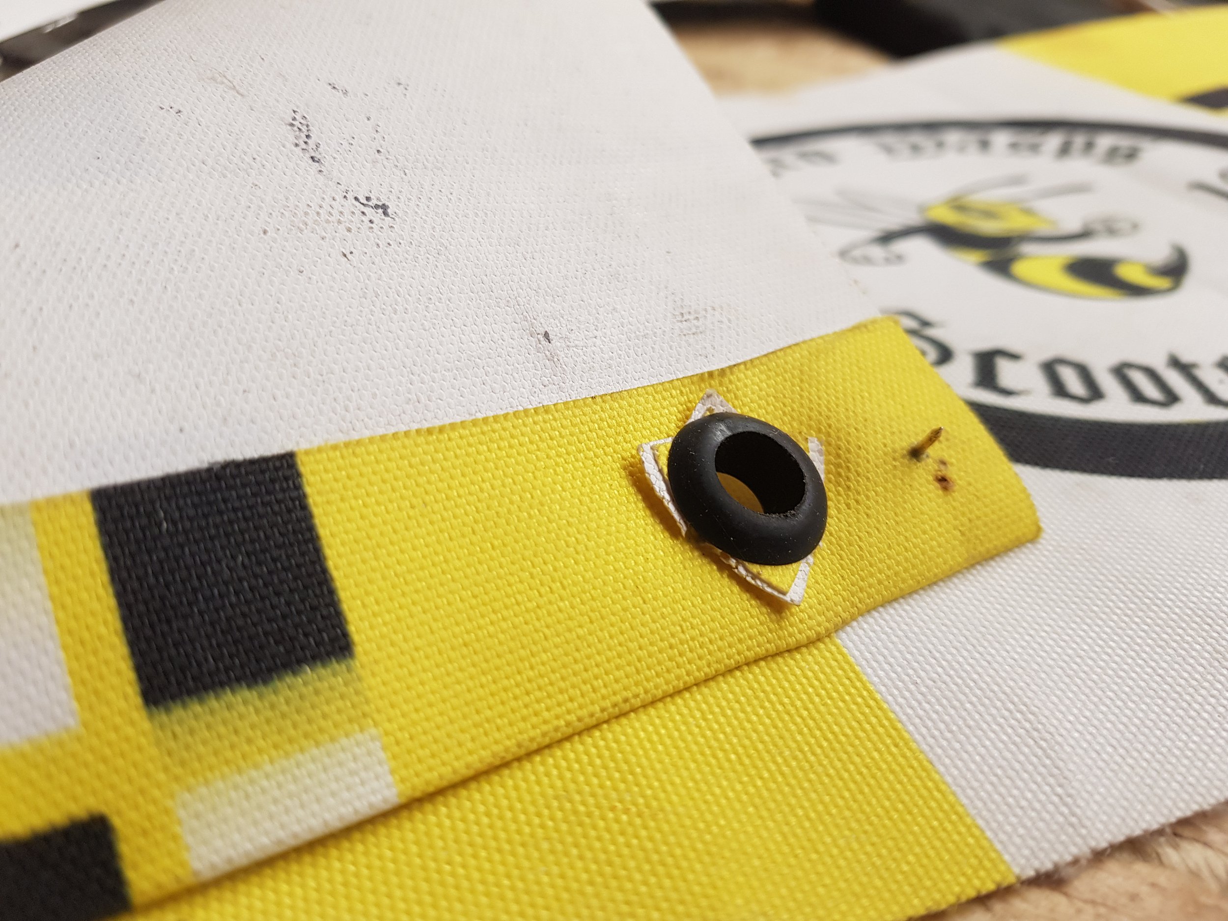A close up of Telford Wasp Scooter Club small cotton banner eyelets.